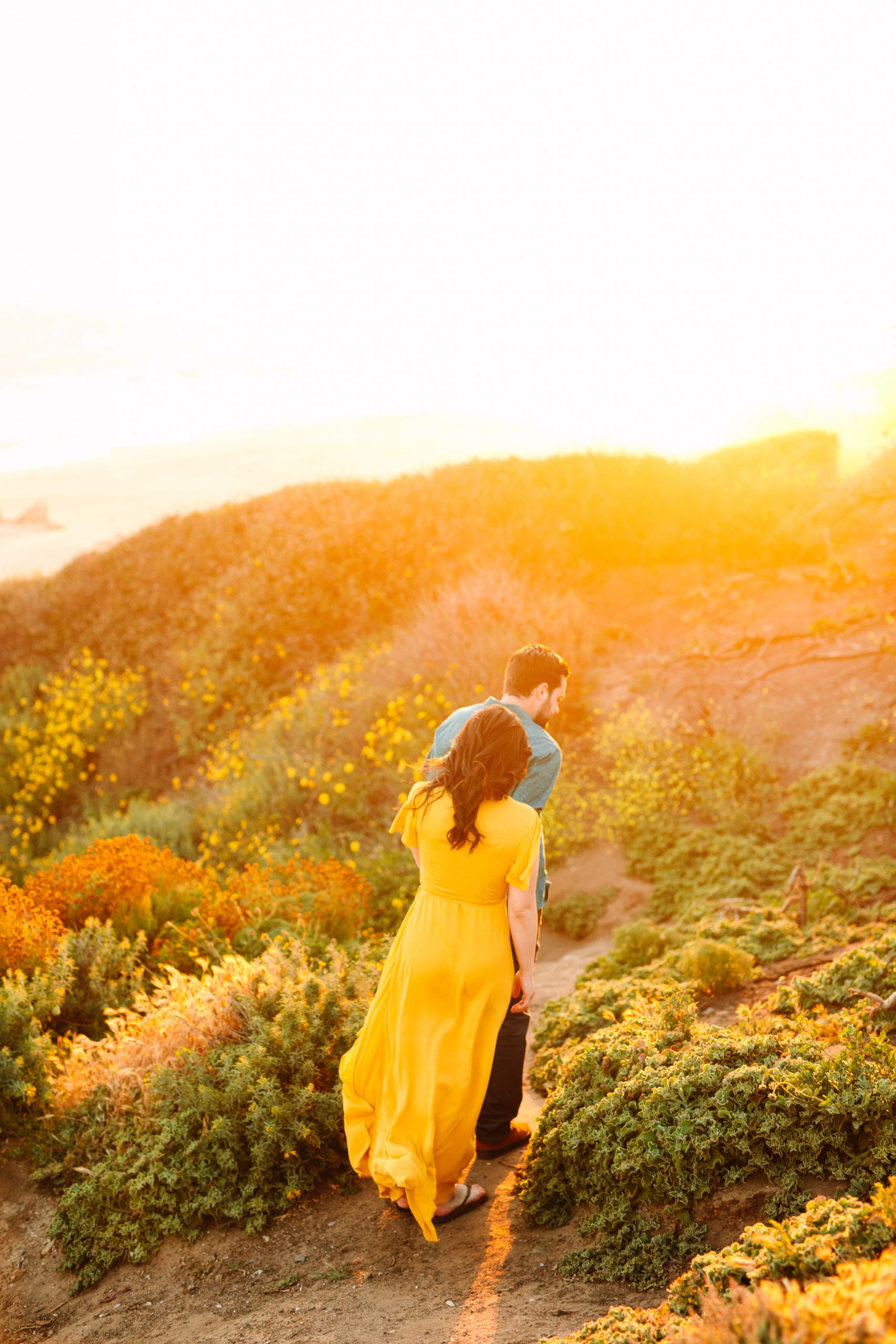 Couple walking to beach in yellow by Mary Costa Photography