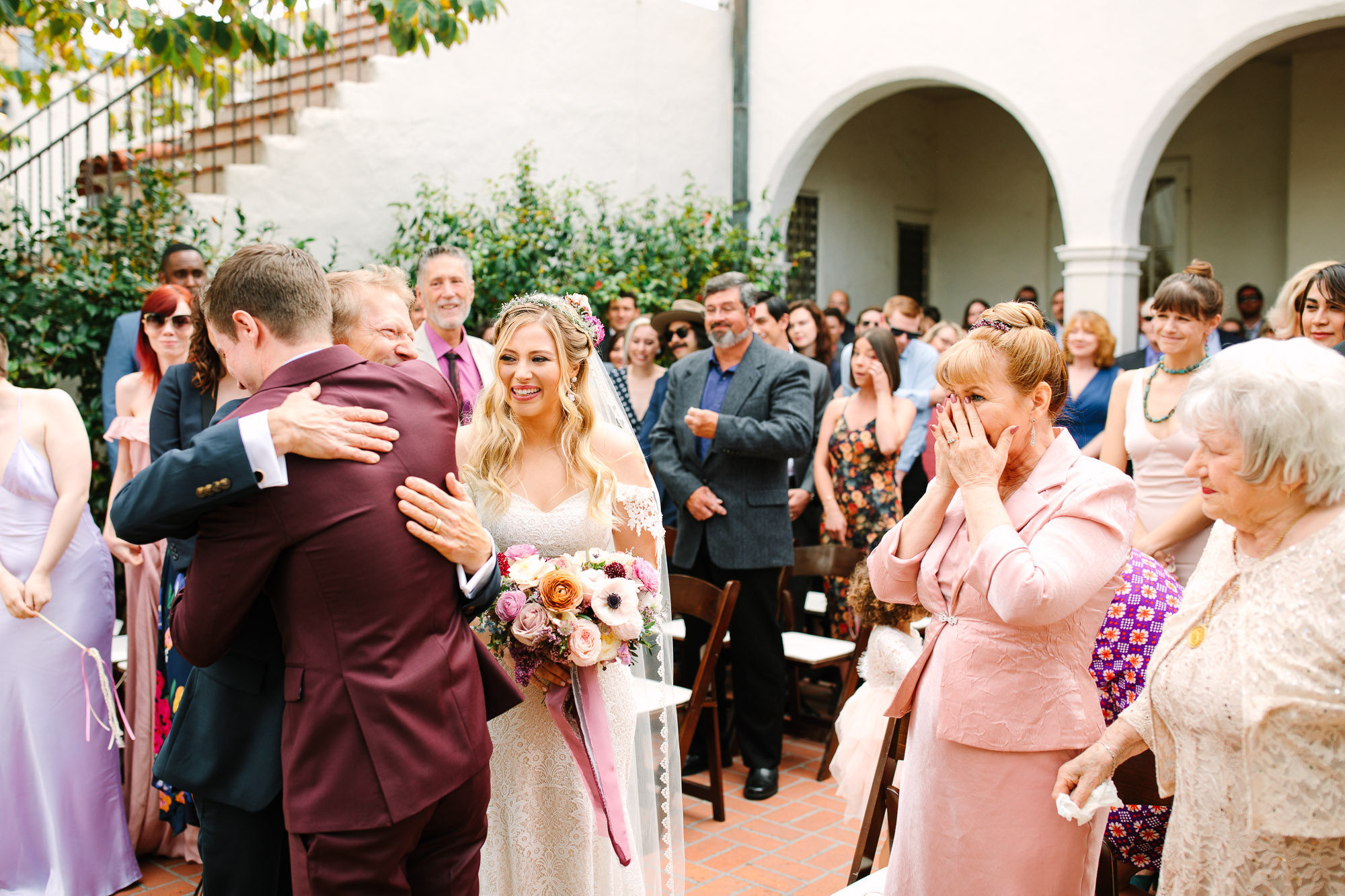 Groom and father of the bride embracing during ceremony by Mary Costa Photography