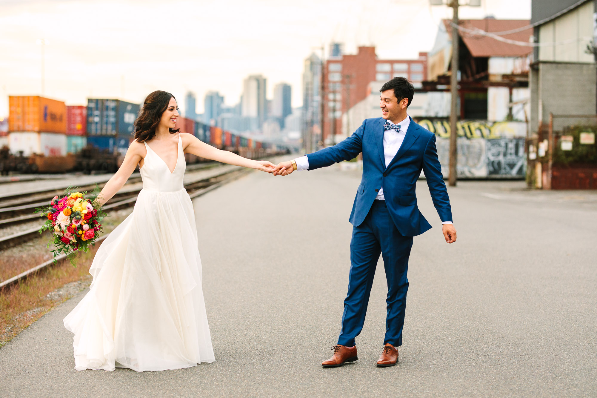 Bride and groom twirling with Seattle backdrop by Mary Costa Photography