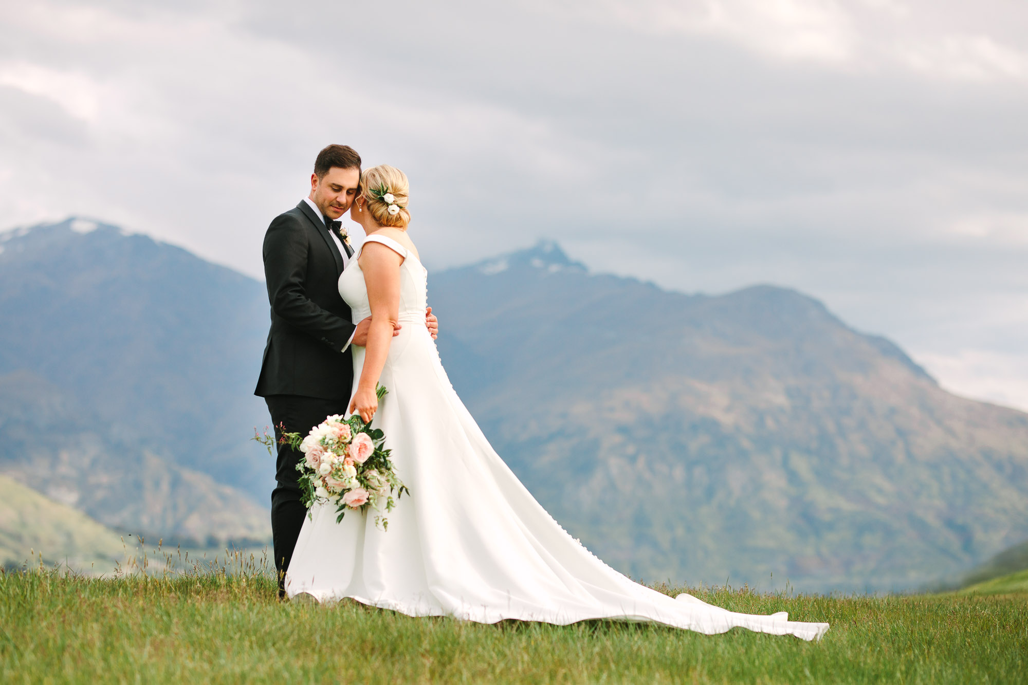 Couple embracing by mountain at Millbrook Resort New Zealand Indian Fusion wedding at Fig House Los Angeles by Mary Costa Photography