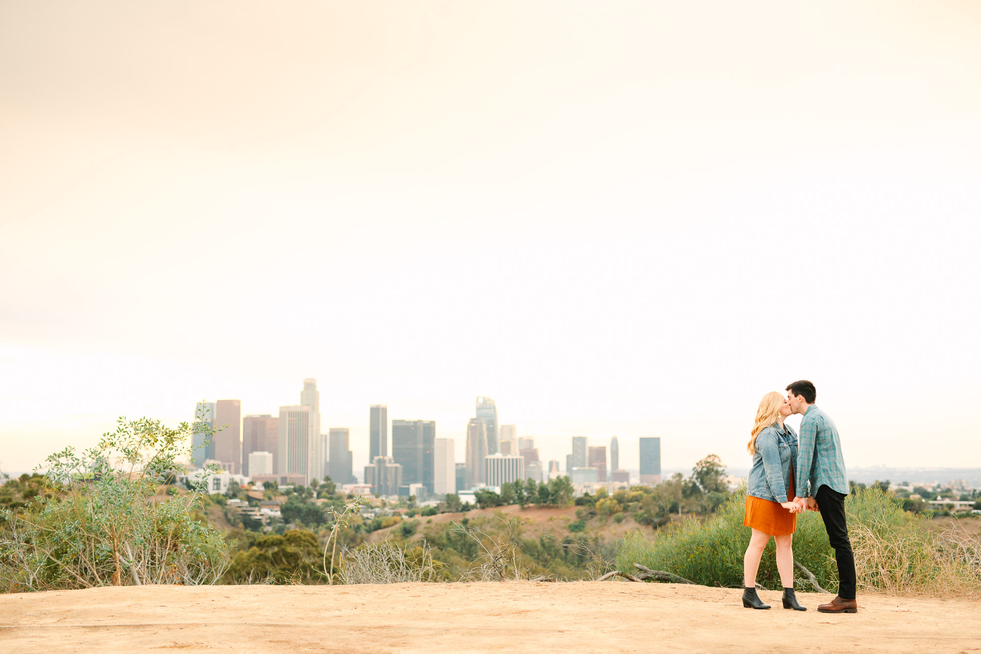 Couple kissing with Los Angeles DTLA skyline Indian Fusion wedding at Fig House Los Angeles by Mary Costa Photography
