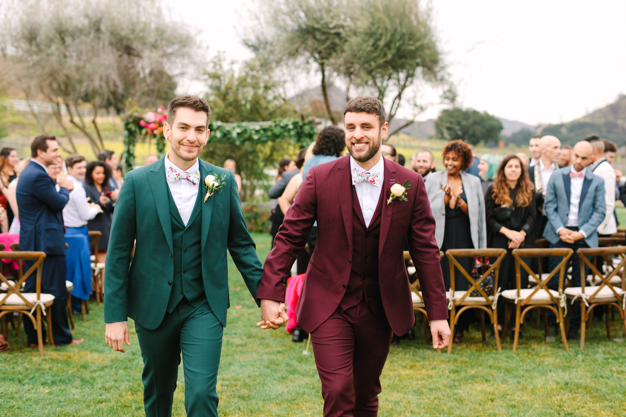 Two grooms leaving wedding ceremony by Mary Costa Photography