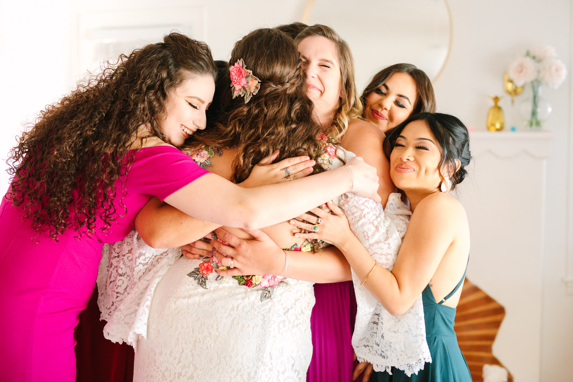 Colorful bridal party hugging Bride's first look with bridesmaids - www.marycostaweddings.com