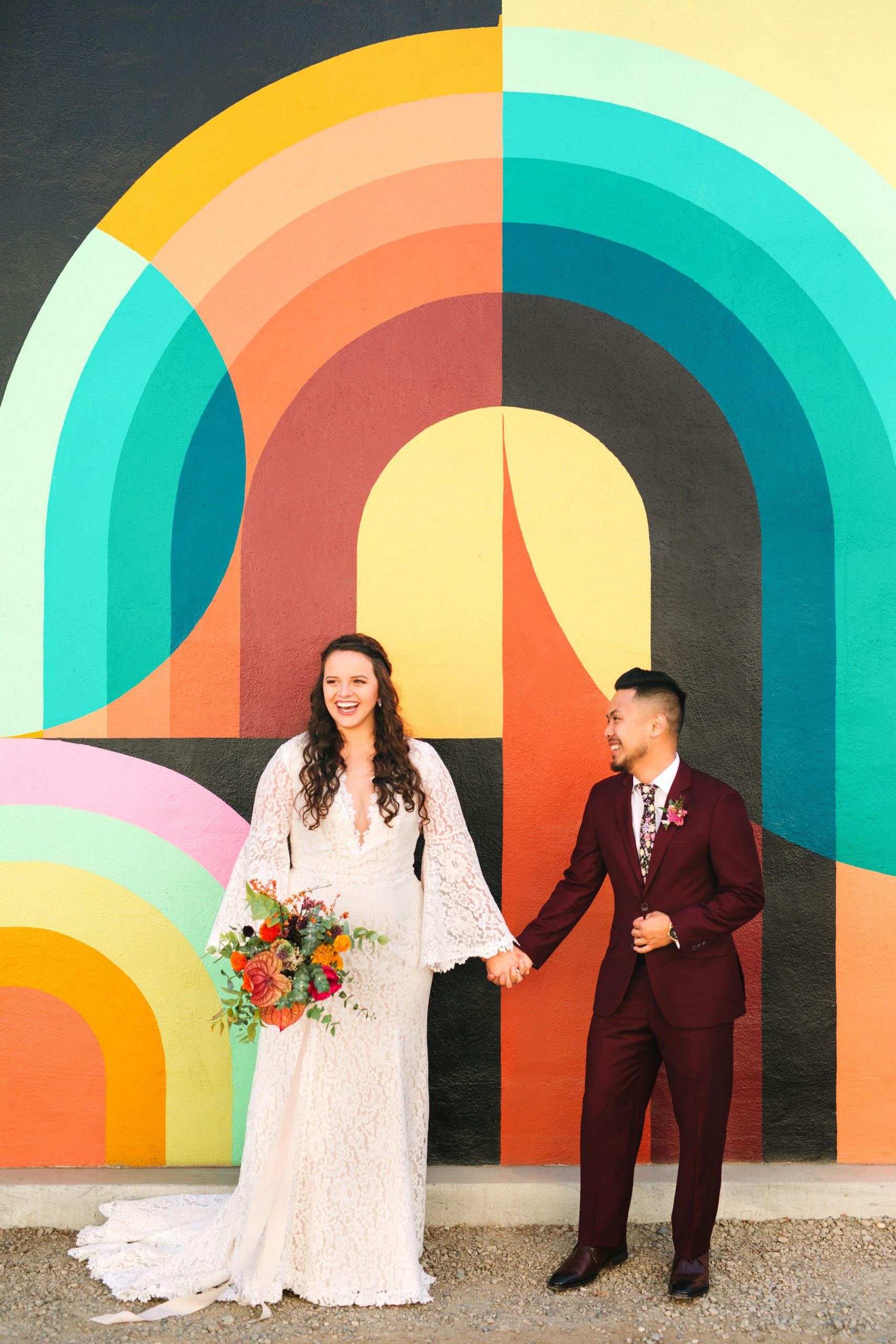 Joyful bride and groom in front of colorful Jessie and Katey mural in Sacramento - www.marycostaweddings.com