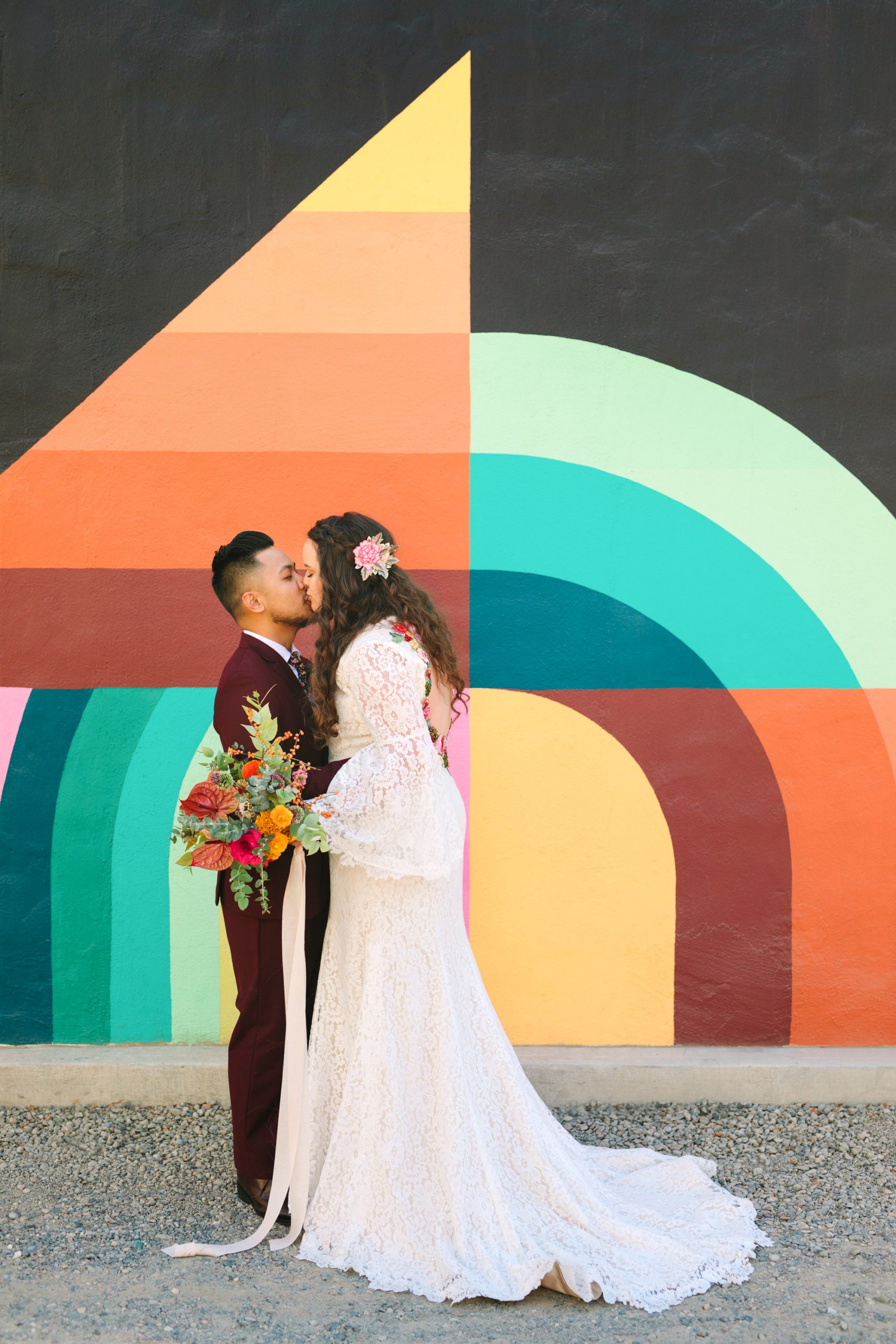 Bride and groom kissing in front of colorful Jessie and Katey mural in Sacramento - www.marycostaweddings.com