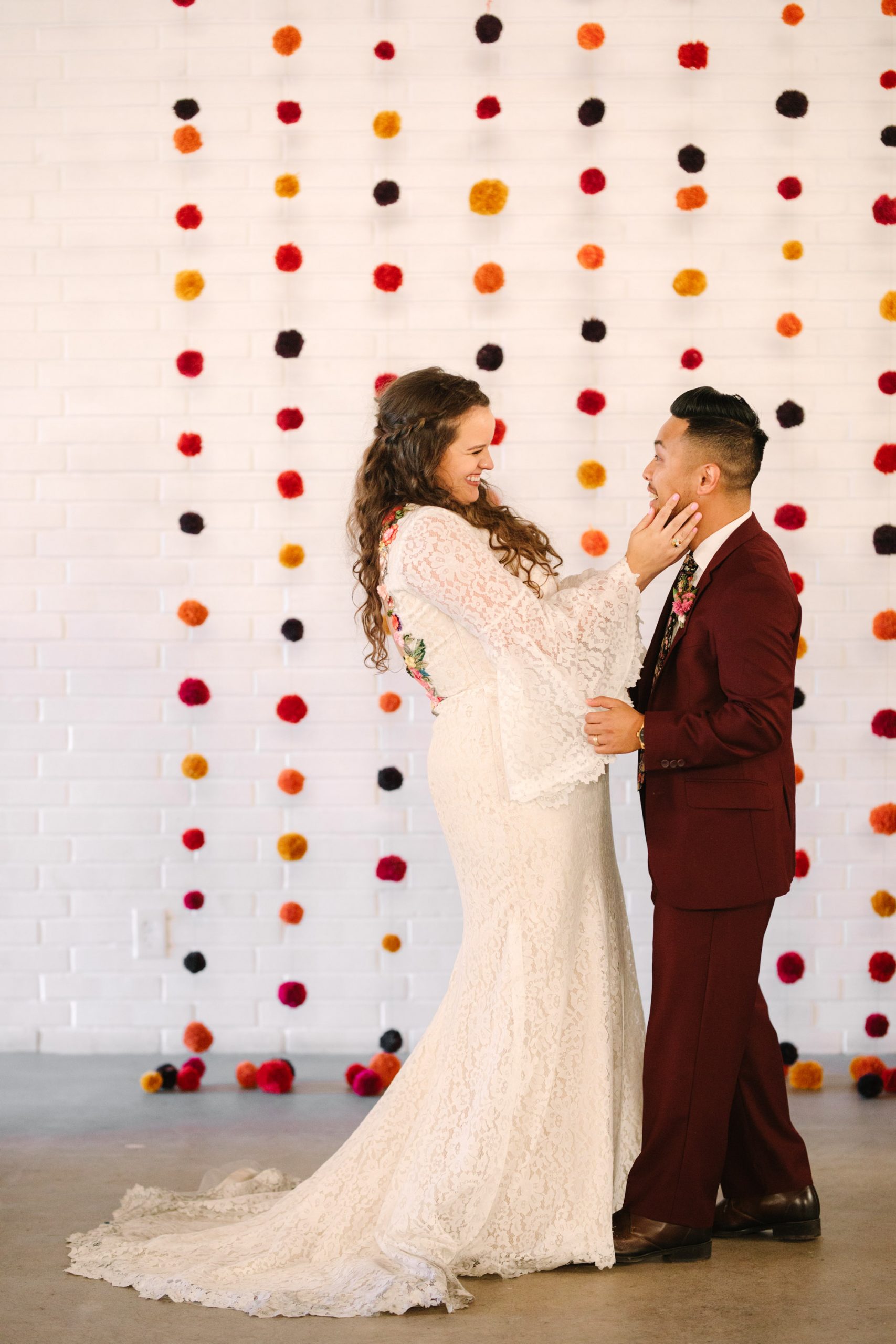 Bride and groom with pom pom backdrop at BLOC Venue Roseville - www.marycostaweddings.com