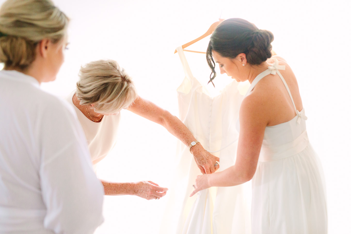 Bride getting dressed in all white. Millbrook Resort Queenstown New Zealand wedding by Mary Costa Photography | www.marycostaweddings.com