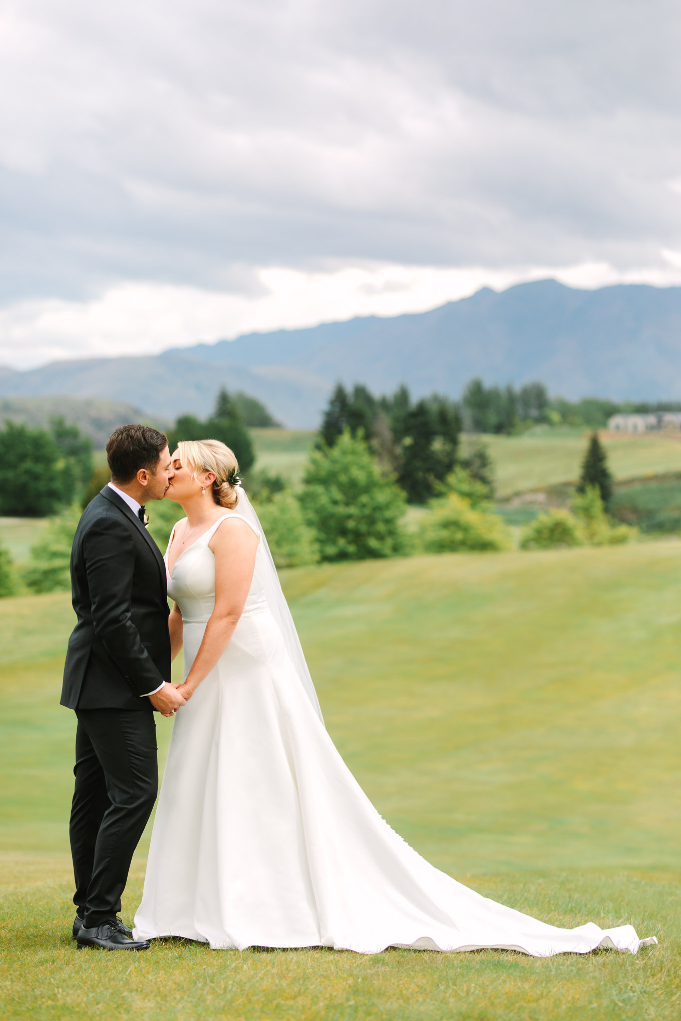 Bride and groom kissing at first look on hillside. Millbrook Resort Queenstown New Zealand wedding by Mary Costa Photography | www.marycostaweddings.com