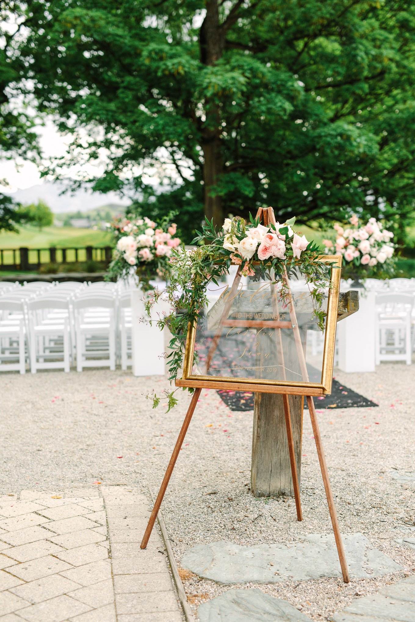 Clear welcome sign at ceremony in gold frame with flowers. Millbrook Resort Queenstown New Zealand wedding by Mary Costa Photography | www.marycostaweddings.com