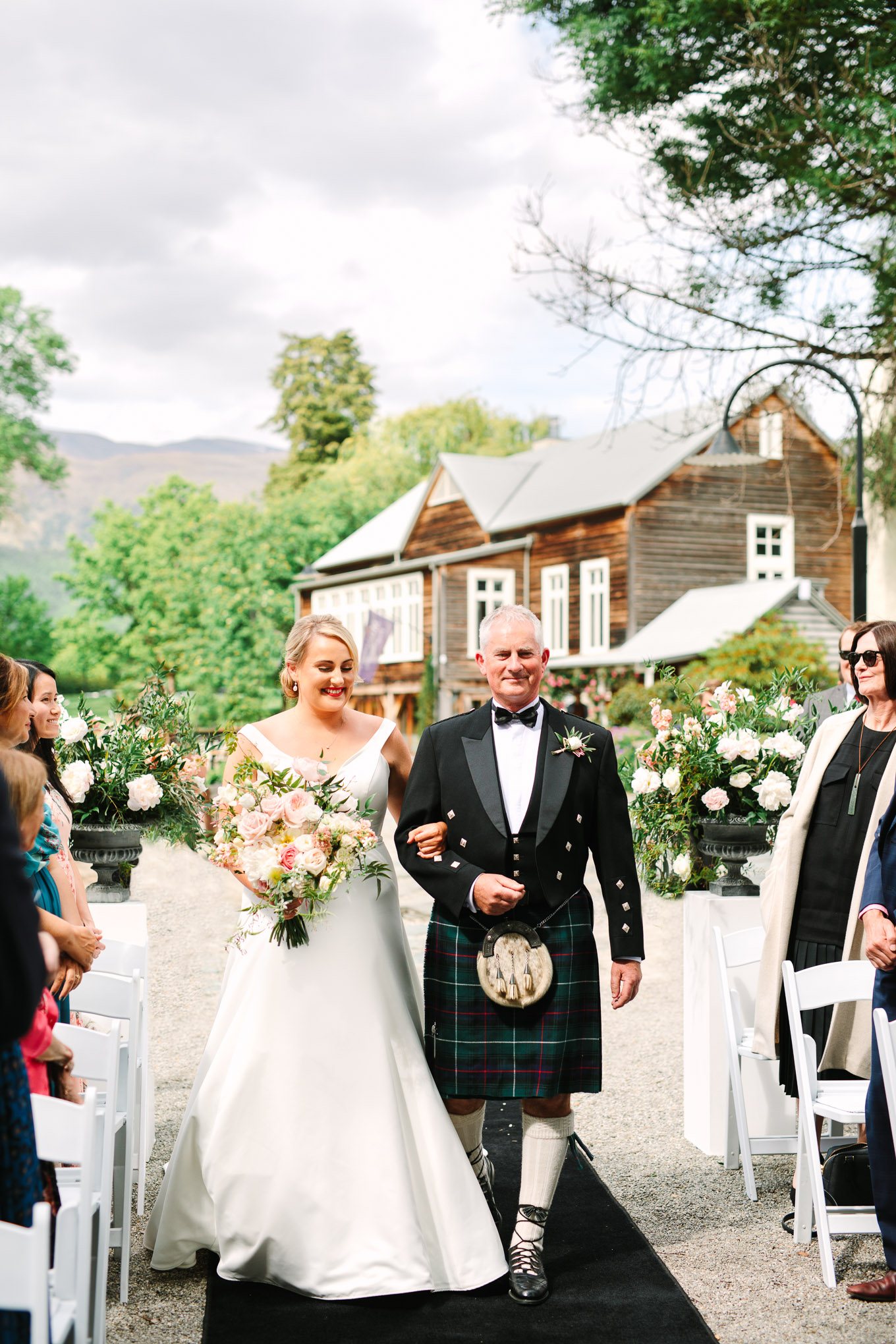 Bride and father in traditional Scottish kilt walking down the aisle at wedding ceremony. Millbrook Resort Queenstown New Zealand wedding by Mary Costa Photography | www.marycostaweddings.com