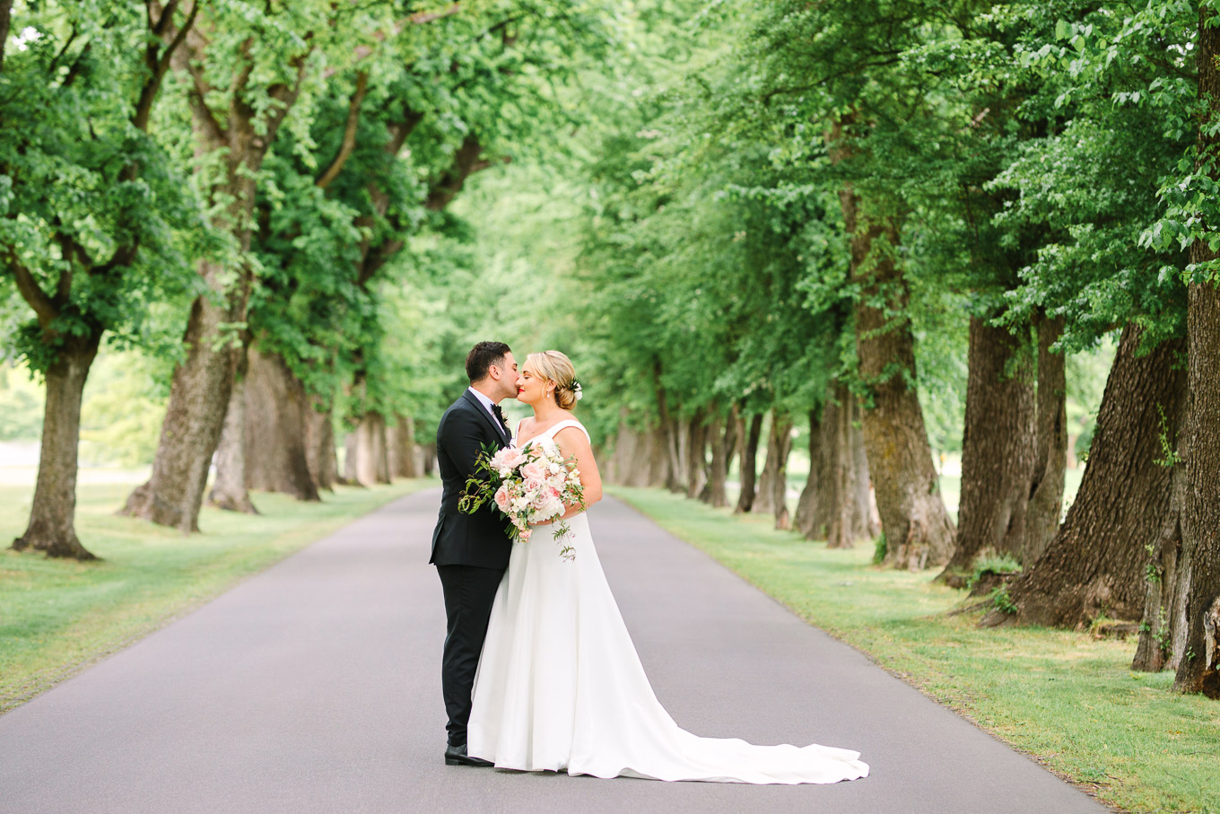 Bride and groom kissing on tree-lined road. Millbrook Resort Queenstown New Zealand wedding by Mary Costa Photography | www.marycostaweddings.com