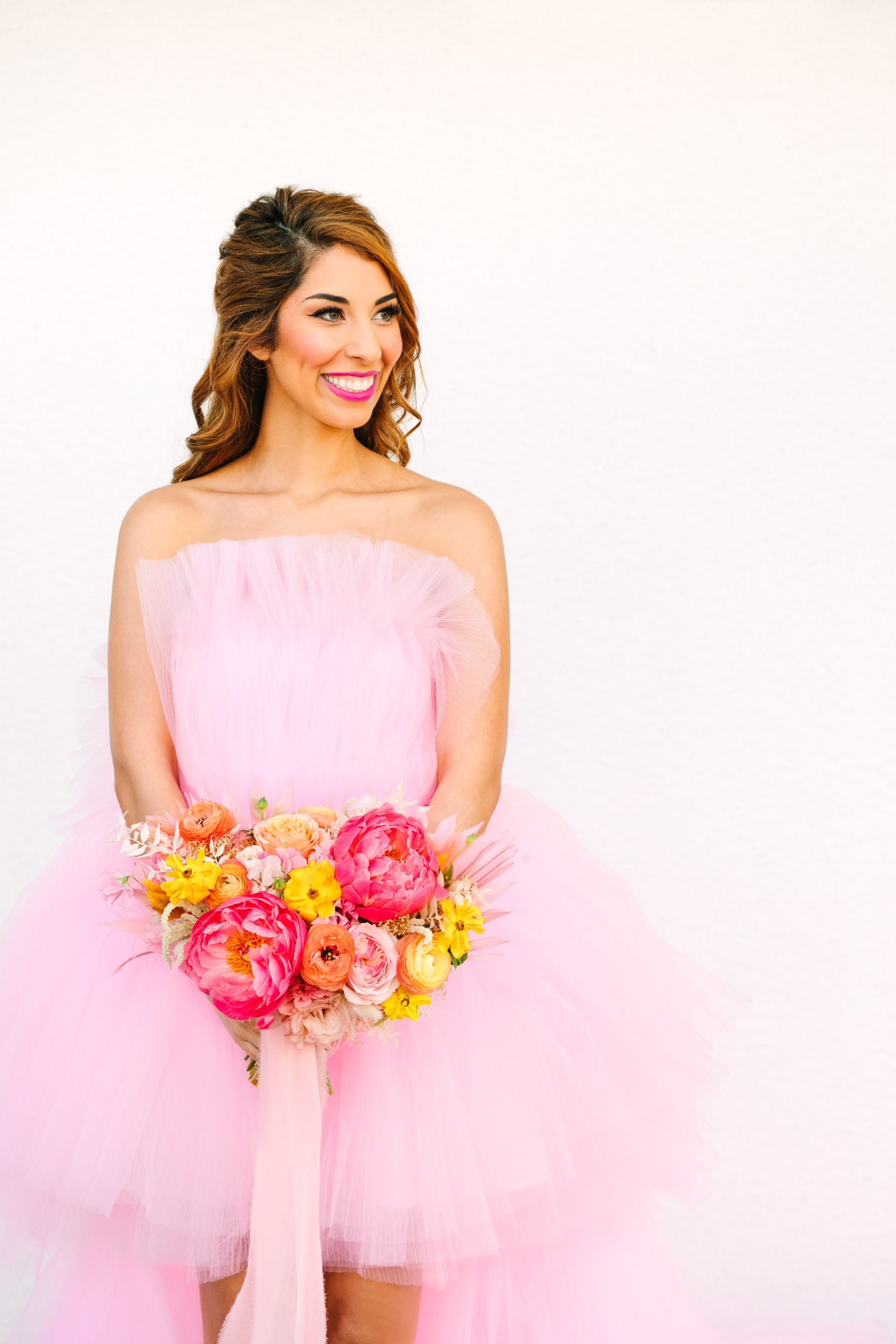 Bride in pink tulle high low gown with pink and yellow bouquet | Pink wedding dress Palm Springs elopement featured on Green Wedding Shoes | Colorful mid-century modern wedding with Saguaro Hotel backdrop | Vibrant and elevated wedding photos for fun-loving couples in Southern California #palmspringswedding #palmspringselopement #pinkwedding #greenweddingshoes Source: Mary Costa Photography | Los Angeles