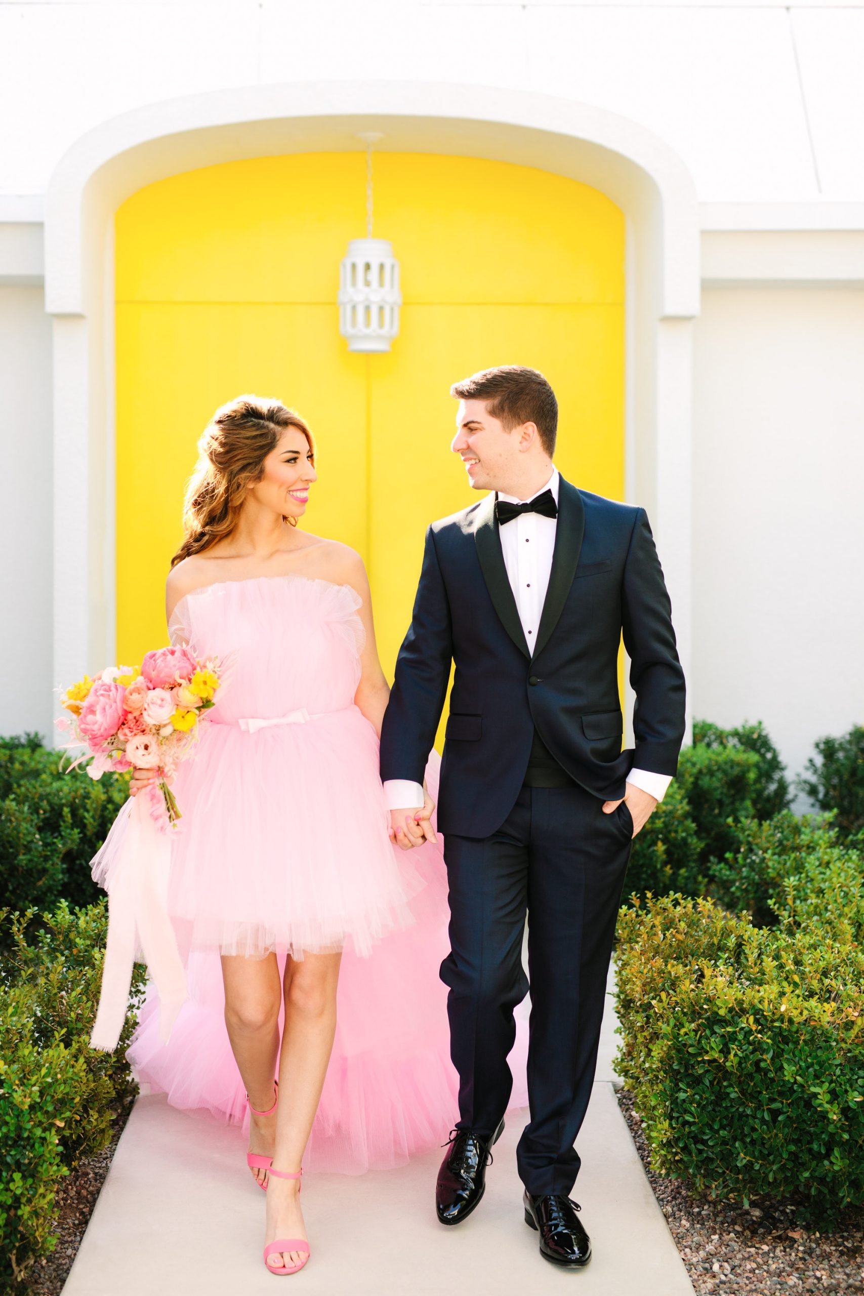 Pink wedding dress Palm Springs elopement featured on Green Wedding Shoes | Colorful mid-century modern wedding with bright yellow door backdrop | Vibrant and elevated wedding photos for fun-loving couples in Southern California #palmspringswedding #palmspringselopement #pinkwedding #greenweddingshoes Source: Mary Costa Photography | Los Angeles