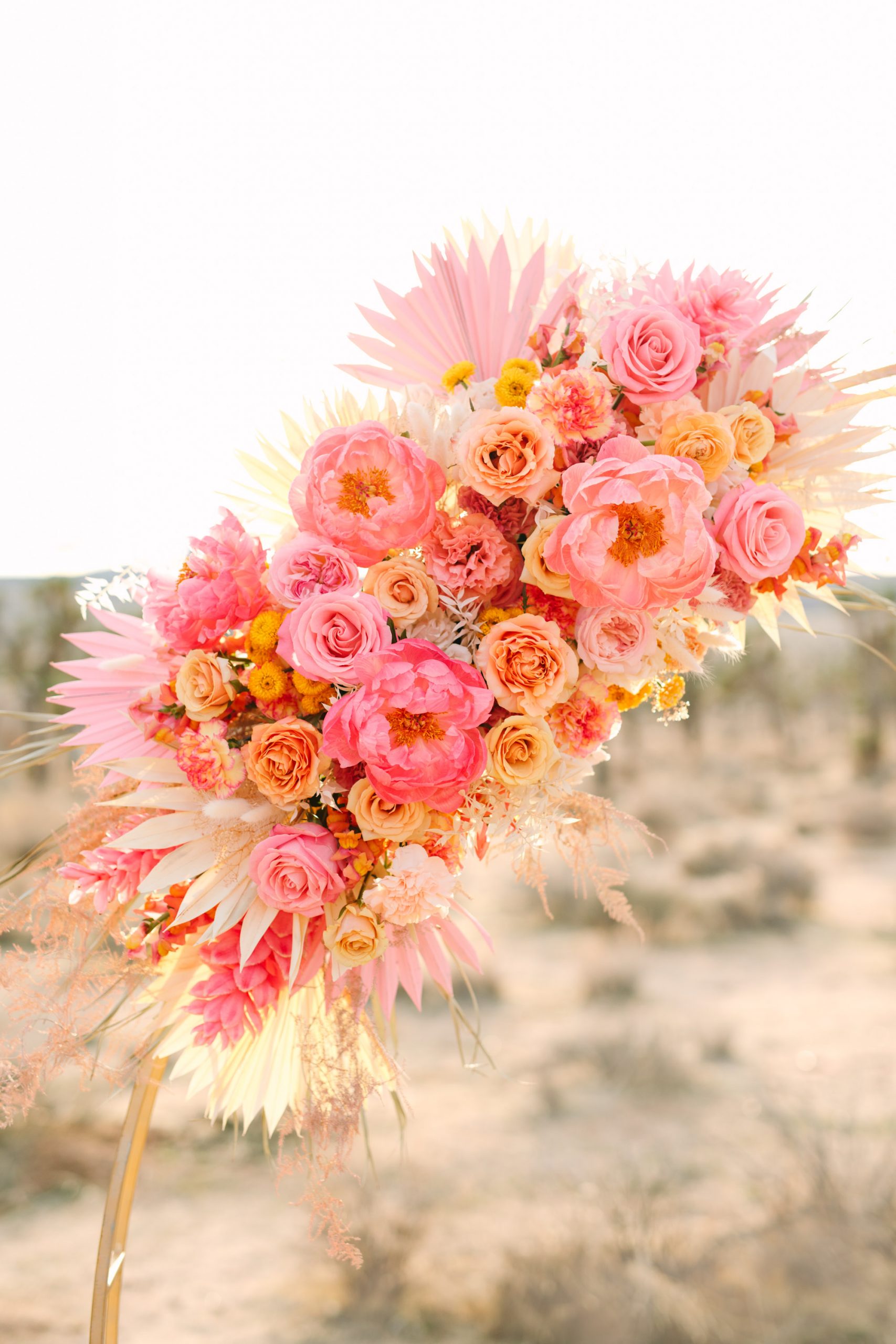 Pink peony and palm ceremony florals | Pink wedding dress Joshua Tree elopement featured on Green Wedding Shoes | Colorful desert wedding inspiration for fun-loving couples in Southern California #joshuatreewedding #joshuatreeelopement #pinkwedding #greenweddingshoes Source: Mary Costa Photography | Los Angeles