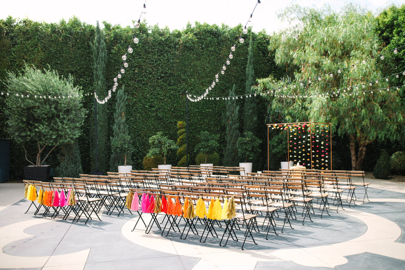 Outdoor ceremony with colorful paper tassels. Two Disney artists create a unique and colorful Indian Fusion wedding at The Fig House Los Angeles, featured on Green Wedding Shoes. | Colorful and elevated wedding inspiration for fun-loving couples in Southern California | #indianwedding #indianfusionwedding #thefighouse #losangeleswedding   Source: Mary Costa Photography | Los Angeles