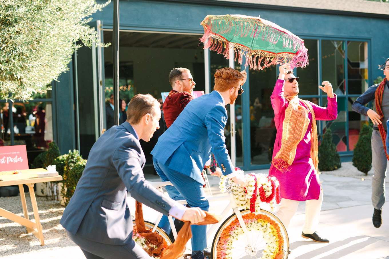 Groom riding into wedding ceremony on white Baraat bicycle. Two Disney artists create a unique and colorful Indian Fusion wedding at The Fig House Los Angeles, featured on Green Wedding Shoes. | Colorful and elevated wedding inspiration for fun-loving couples in Southern California | #indianwedding #indianfusionwedding #thefighouse #losangeleswedding   Source: Mary Costa Photography | Los Angeles