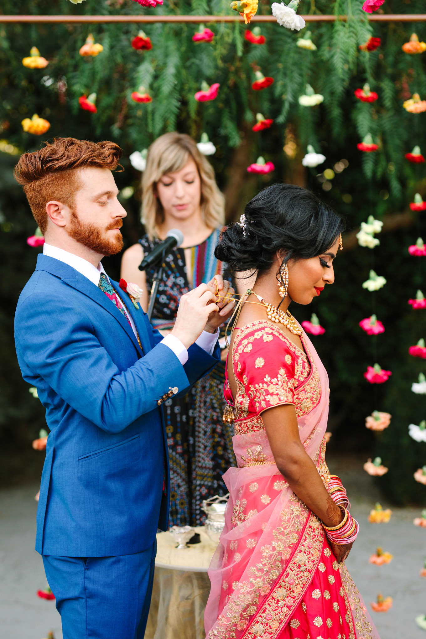 Groom putting necklace on bride during wedding ceremony. Two Disney artists create a unique and colorful Indian Fusion wedding at The Fig House Los Angeles, featured on Green Wedding Shoes. | Colorful and elevated wedding inspiration for fun-loving couples in Southern California | #indianwedding #indianfusionwedding #thefighouse #losangeleswedding   Source: Mary Costa Photography | Los Angeles