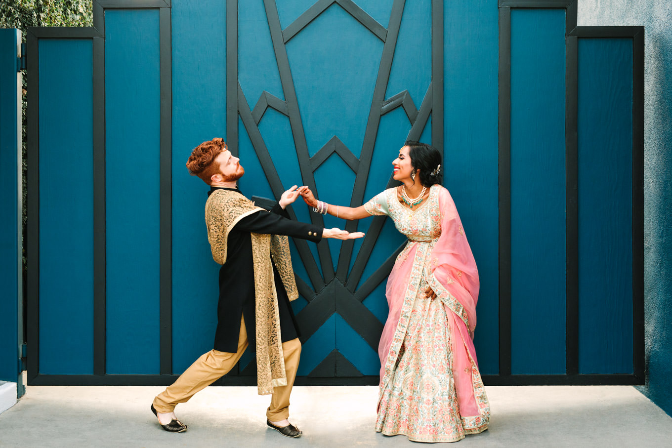 Bride and groom being playful in front of geometric wall. Two Disney artists create a unique and colorful Indian Fusion wedding at The Fig House Los Angeles, featured on Green Wedding Shoes. | Colorful and elevated wedding inspiration for fun-loving couples in Southern California | #indianwedding #indianfusionwedding #thefighouse #losangeleswedding   Source: Mary Costa Photography | Los Angeles