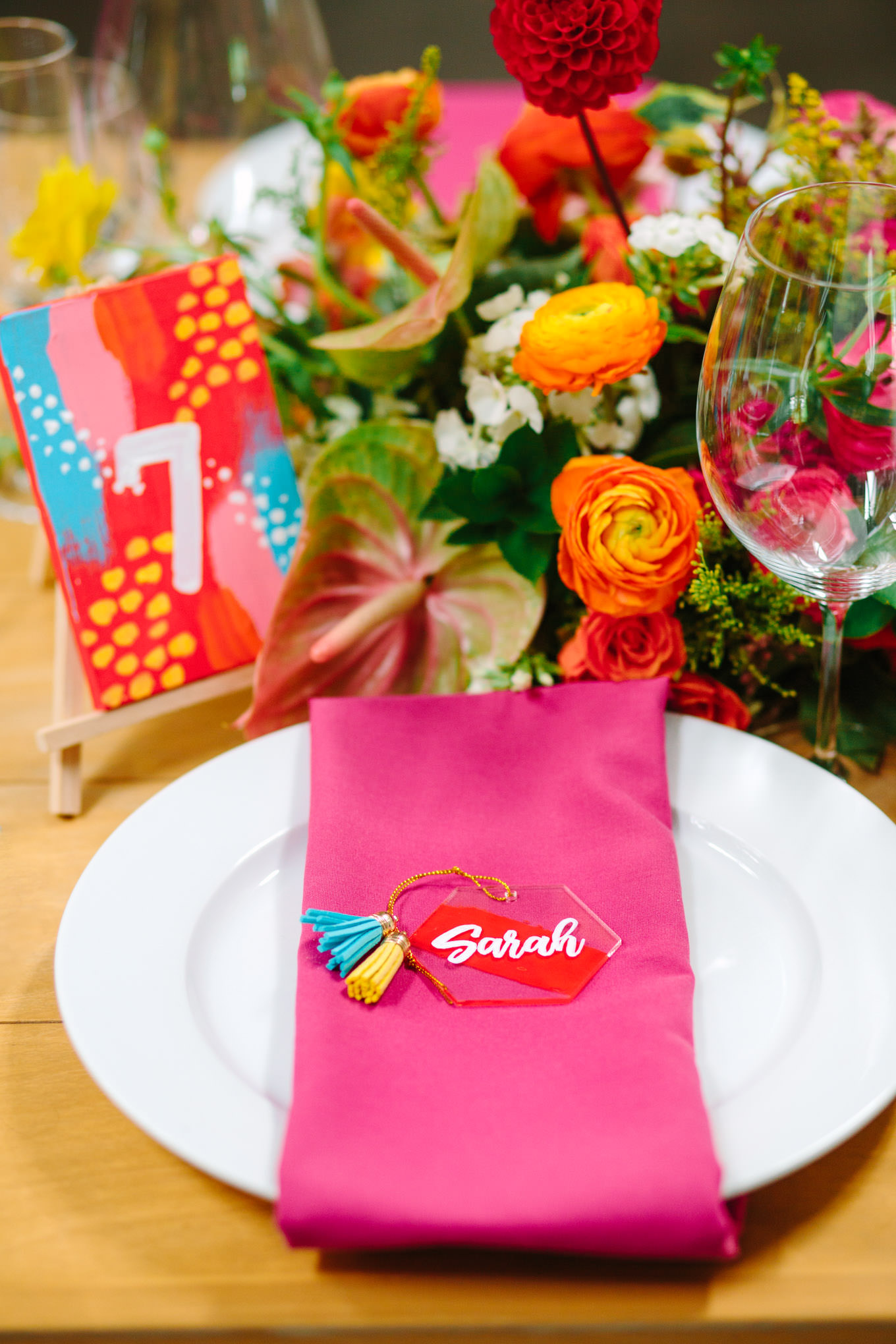 Hot pink napkin, tassel name, and hand-painted table number. Two Disney artists create a unique and colorful Indian Fusion wedding at The Fig House Los Angeles, featured on Green Wedding Shoes. | Colorful and elevated wedding inspiration for fun-loving couples in Southern California | #indianwedding #indianfusionwedding #thefighouse #losangeleswedding   Source: Mary Costa Photography | Los Angeles
