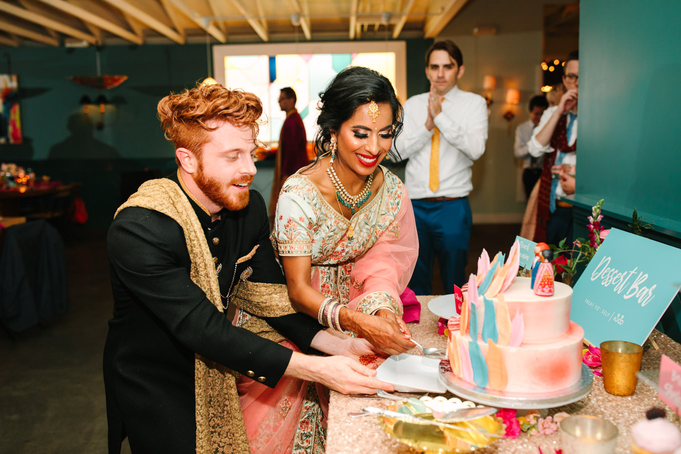Bride and groom cutting colorful cake. Two Disney artists create a unique and colorful Indian Fusion wedding at The Fig House Los Angeles, featured on Green Wedding Shoes. | Colorful and elevated wedding inspiration for fun-loving couples in Southern California | #indianwedding #indianfusionwedding #thefighouse #losangeleswedding   Source: Mary Costa Photography | Los Angeles