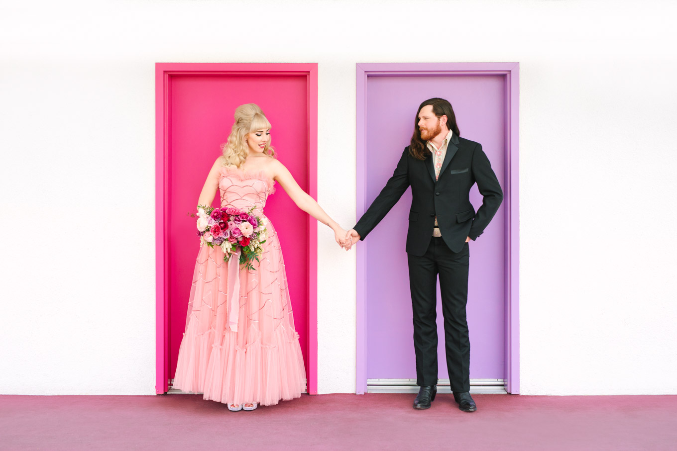 Retro couple with colorful Saguaro Hotel doors. Modern vintage-inspired Palm Springs engagement session with a 1960s pink Cadillac, retro clothing, and flowers by Shindig Chic. | Colorful and elevated wedding inspiration for fun-loving couples in Southern California | #engagementsession #PalmSpringsengagement #vintageweddingdress #floralcar #pinkcar   Source: Mary Costa Photography | Los Angeles