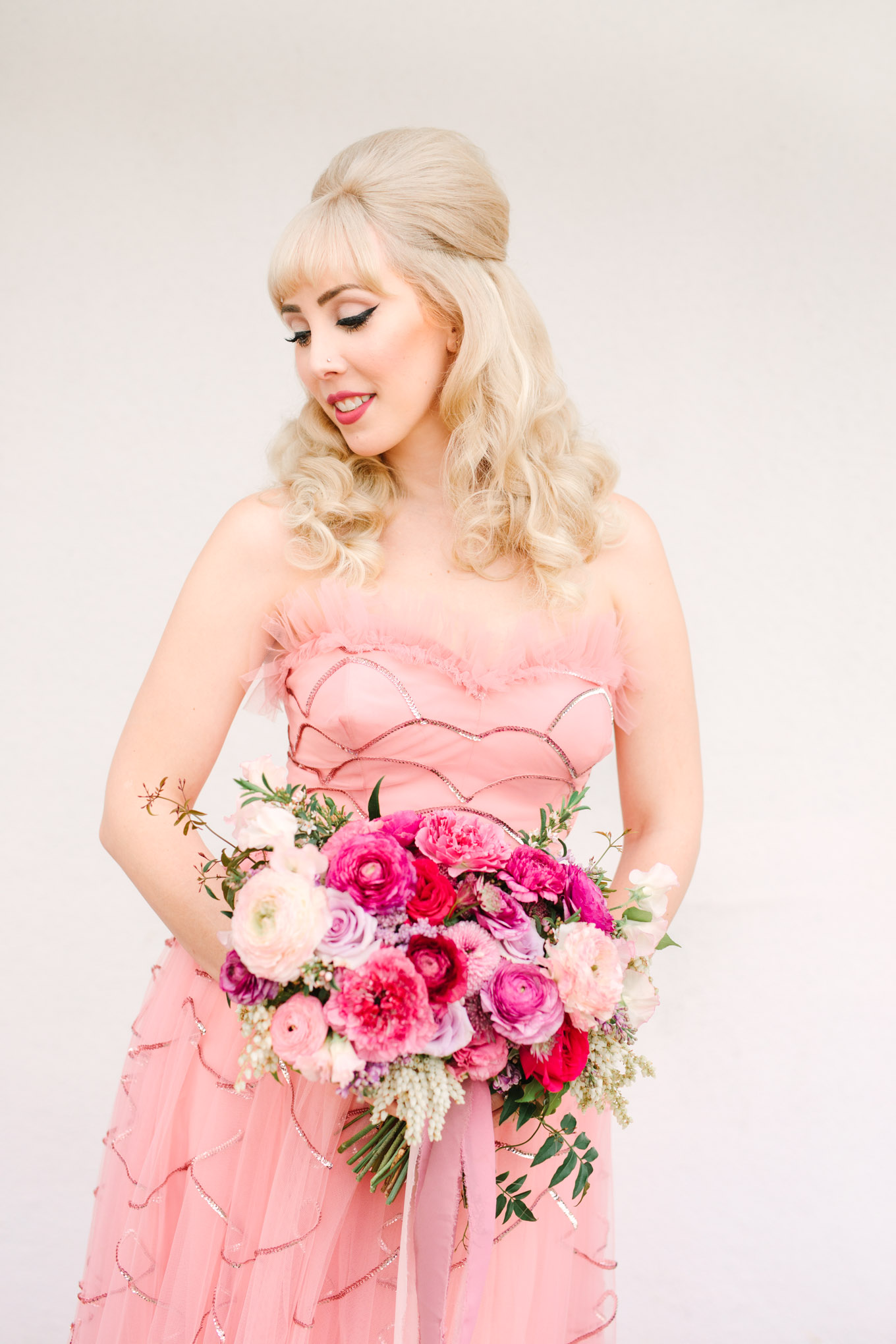 Retro bride in pink vintage gown. Modern vintage-inspired Palm Springs engagement session with a 1960s pink Cadillac, retro clothing, and flowers by Shindig Chic. | Colorful and elevated wedding inspiration for fun-loving couples in Southern California | #engagementsession #PalmSpringsengagement #vintageweddingdress #floralcar #pinkcar   Source: Mary Costa Photography | Los Angeles