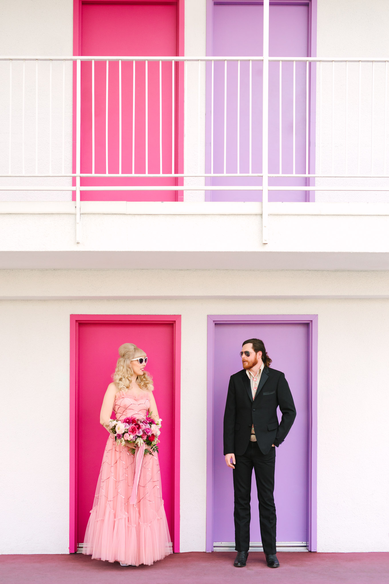 Retro couple with pink and lavender Saguaro Hotel. Modern vintage-inspired Palm Springs engagement session with a 1960s pink Cadillac, retro clothing, and flowers by Shindig Chic. | Colorful and elevated wedding inspiration for fun-loving couples in Southern California | #engagementsession #PalmSpringsengagement #vintageweddingdress #floralcar #pinkcar   Source: Mary Costa Photography | Los Angeles