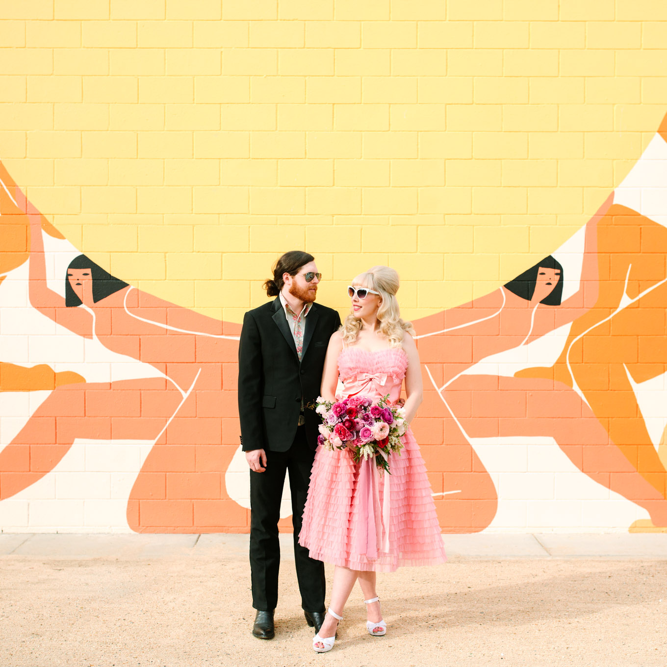 Colorful Ace Hotel portrait. Modern vintage-inspired Palm Springs engagement session with a 1960s pink Cadillac, retro clothing, and flowers by Shindig Chic. | Colorful and elevated wedding inspiration for fun-loving couples in Southern California | #engagementsession #PalmSpringsengagement #vintageweddingdress #floralcar #pinkcar   Source: Mary Costa Photography | Los Angeles