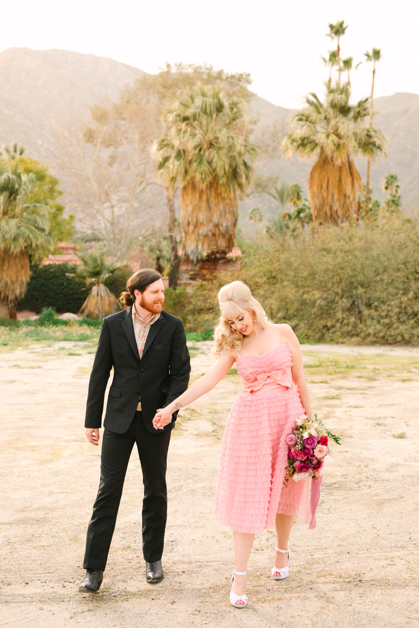 Modern vintage-inspired Palm Springs engagement session with a 1960s pink Cadillac, retro clothing, and flowers by Shindig Chic. | Colorful and elevated wedding inspiration for fun-loving couples in Southern California | #engagementsession #PalmSpringsengagement #vintageweddingdress #floralcar #pinkcar   Source: Mary Costa Photography | Los Angeles
