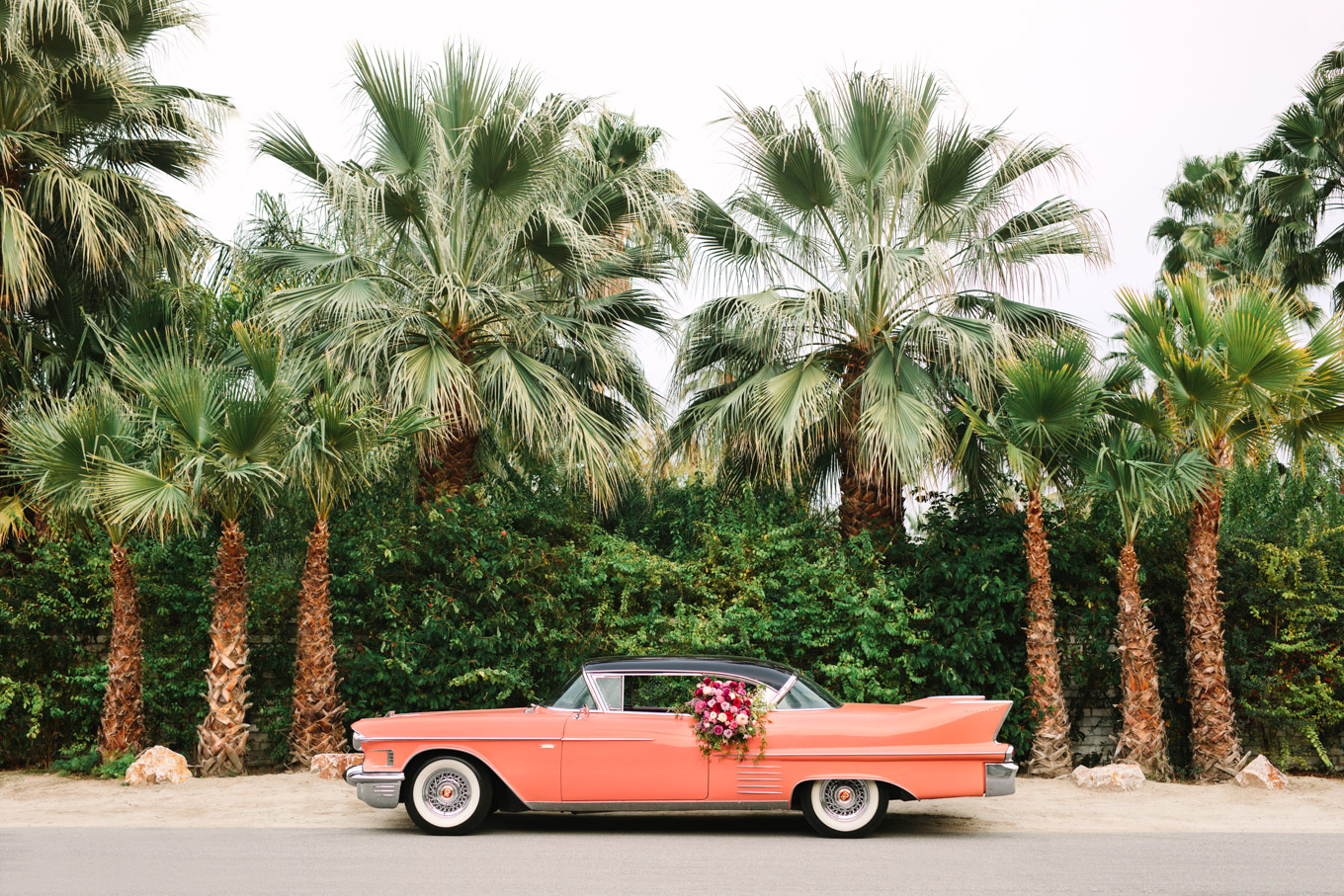 Casa de Monte Vista exterior. Modern vintage-inspired Palm Springs engagement session with a 1960s pink Cadillac, retro clothing, and flowers by Shindig Chic. | Colorful and elevated wedding inspiration for fun-loving couples in Southern California | #engagementsession #PalmSpringsengagement #vintageweddingdress #floralcar #pinkcar   Source: Mary Costa Photography | Los Angeles