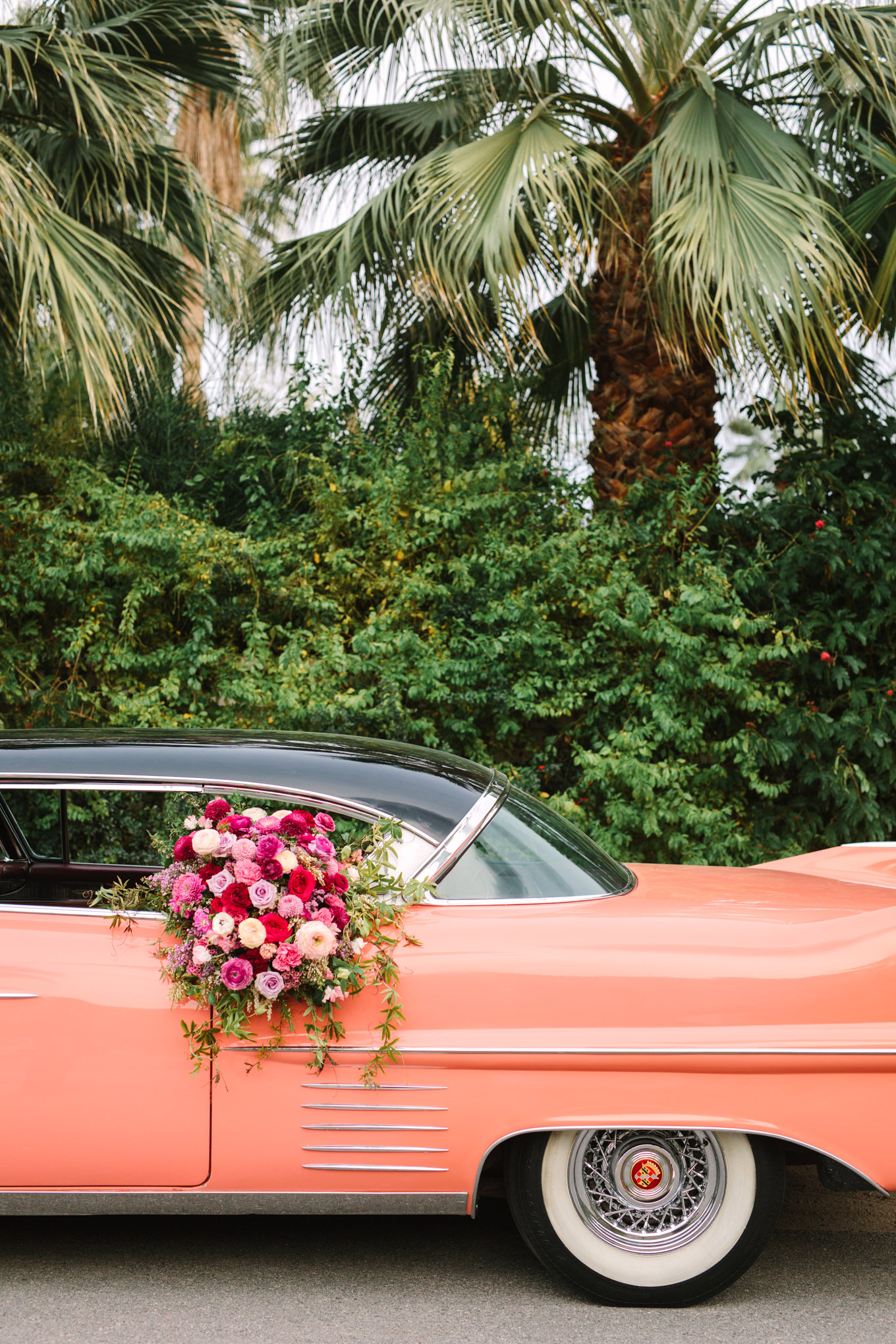 Car flower detail. Modern vintage-inspired Palm Springs engagement session with a 1960s pink Cadillac, retro clothing, and flowers by Shindig Chic. | Colorful and elevated wedding inspiration for fun-loving couples in Southern California | #engagementsession #PalmSpringsengagement #vintageweddingdress #floralcar #pinkcar   Source: Mary Costa Photography | Los Angeles