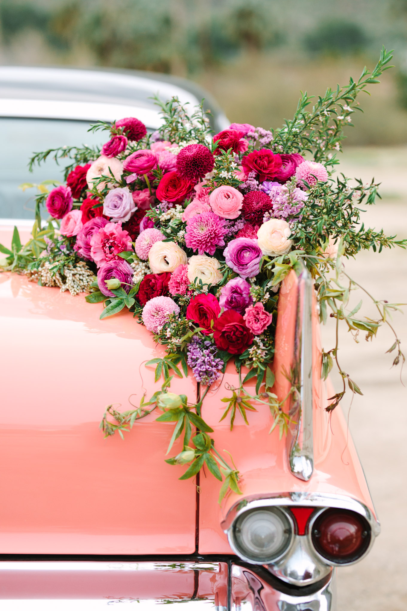 Back of car flower details. Modern vintage-inspired Palm Springs engagement session with a 1960s pink Cadillac, retro clothing, and flowers by Shindig Chic. | Colorful and elevated wedding inspiration for fun-loving couples in Southern California | #engagementsession #PalmSpringsengagement #vintageweddingdress #floralcar #pinkcar   Source: Mary Costa Photography | Los Angeles