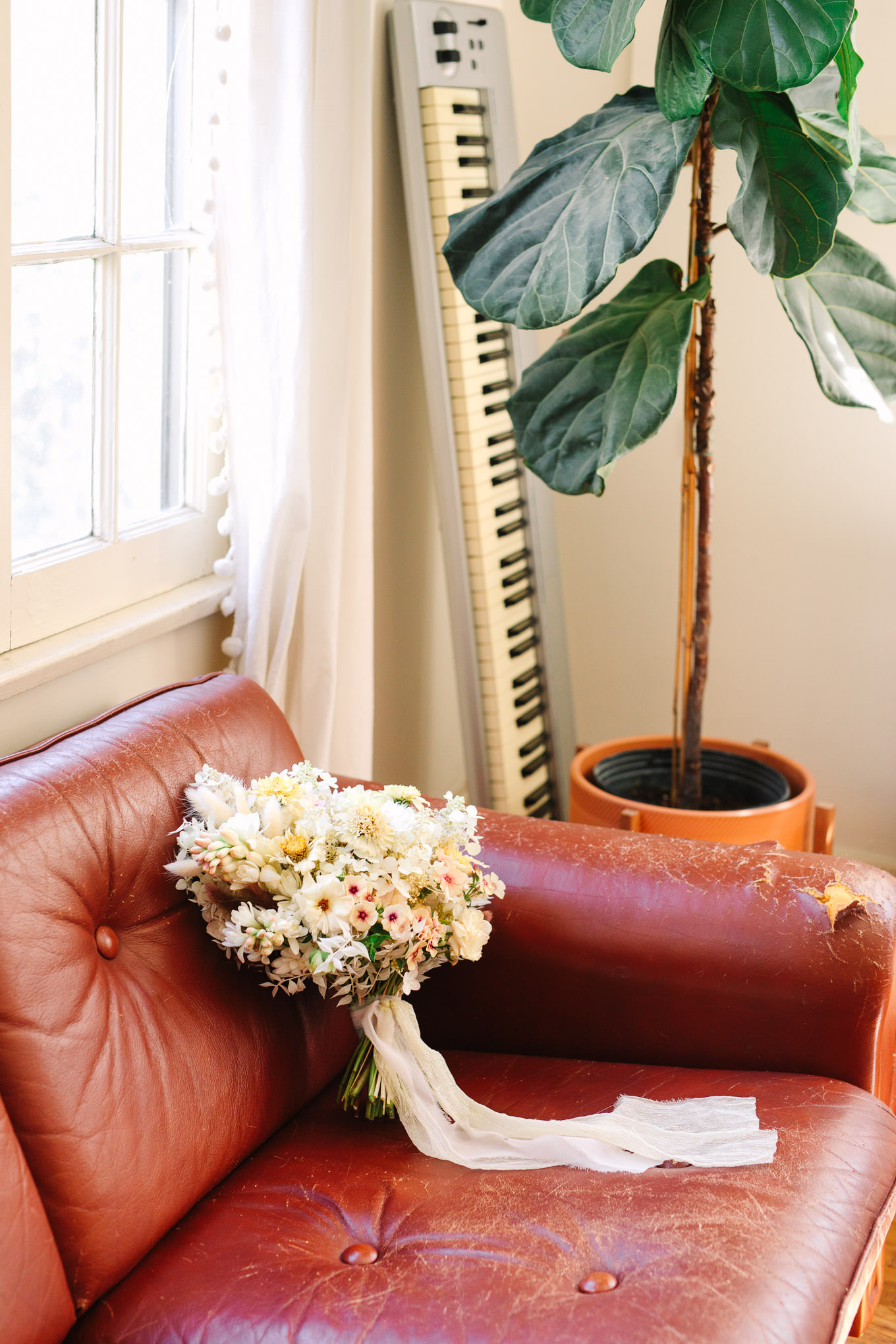Neutral boho wedding bouquet on leather couch | Los Angeles Arboretum Elopement | Colorful and elevated wedding photography for fun-loving couples in Southern California | #LosAngelesElopement #elopement #LAarboretum #LAskyline #elopementphotos   Source: Mary Costa Photography | Los Angeles