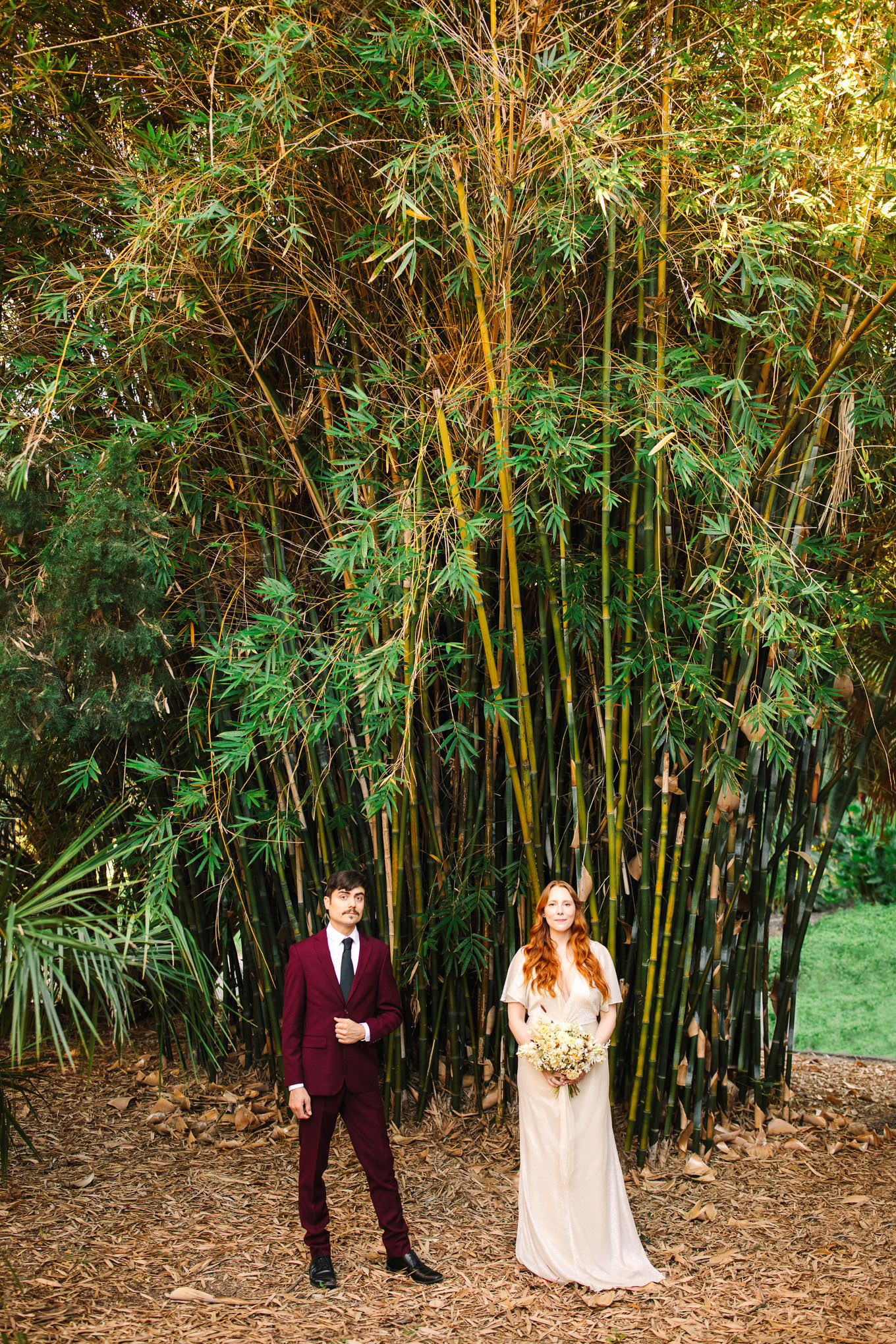 Bride and groom standing in front of bamboo plants