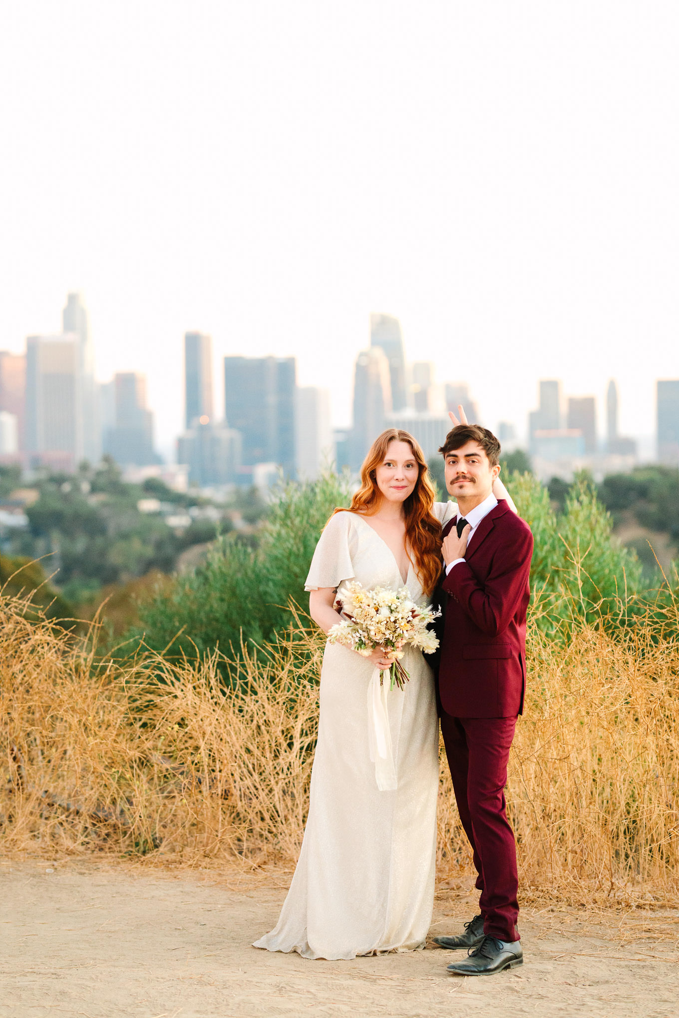 Playful couple giving bunny ears in front of LA skyline | Los Angeles Elysian Park Elopement | Colorful and elevated wedding photography for fun-loving couples in Southern California | #LosAngelesElopement #elopement #LAarboretum #LAskyline #elopementphotos   Source: Mary Costa Photography | Los Angeles