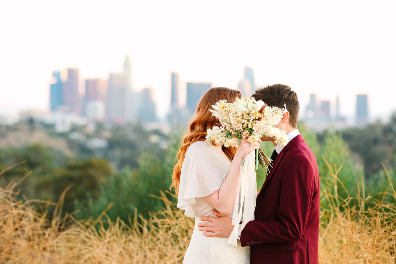 Couple with boho dried bouquet in front of LA skyline | Los Angeles Elysian Park Elopement | Colorful and elevated wedding photography for fun-loving couples in Southern California | #LosAngelesElopement #elopement #LAarboretum #LAskyline #elopementphotos   Source: Mary Costa Photography | Los Angeles