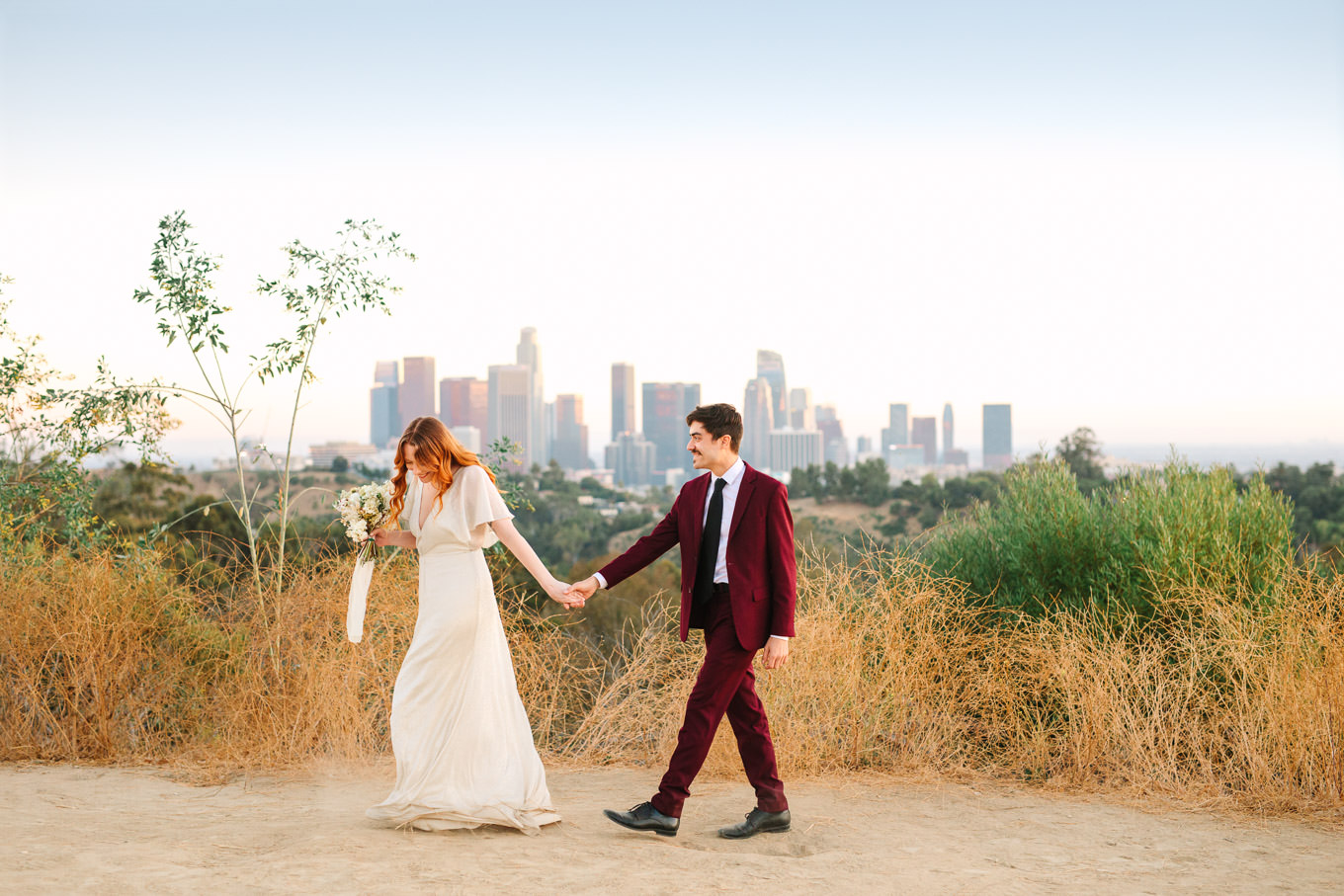 Couple walking in front of LA skyline | Los Angeles Elysian Park Elopement | Colorful and elevated wedding photography for fun-loving couples in Southern California | #LosAngelesElopement #elopement #LAarboretum #LAskyline #elopementphotos   Source: Mary Costa Photography | Los Angeles