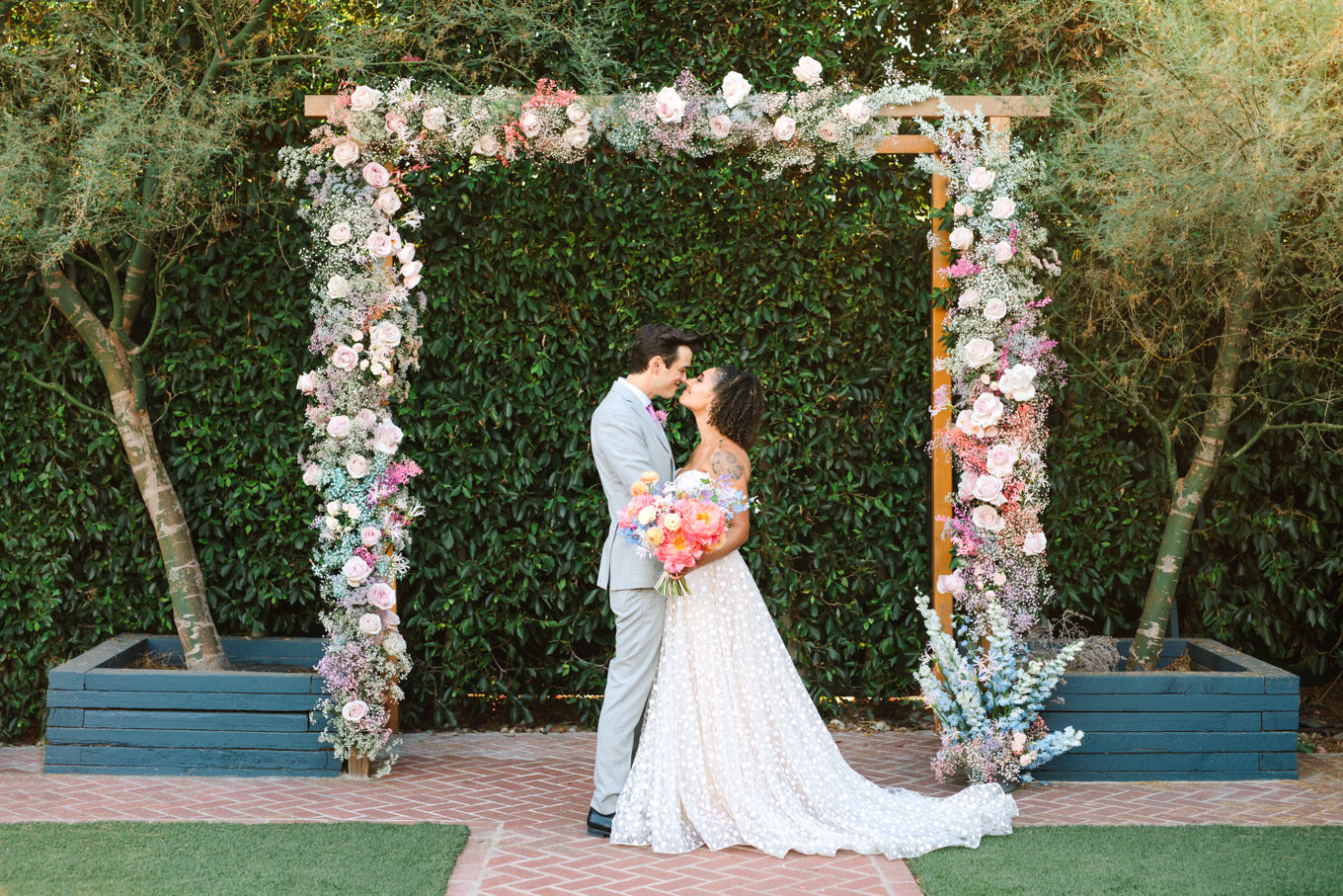 Wedding portrait under rectangular floral arch at Ruby Street | Colorful pop-up micro wedding at The Ruby Street Los Angeles featured on Green Wedding Shoes | Colorful and elevated photography for fun-loving couples in Southern California | #colorfulwedding #popupwedding #weddingphotography #microwedding Source: Mary Costa Photography | Los Angeles