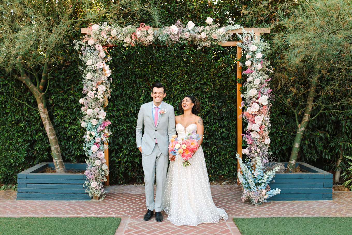 Joyful wedding portrait under ceremony arch | Colorful pop-up micro wedding at The Ruby Street Los Angeles featured on Green Wedding Shoes | Colorful and elevated photography for fun-loving couples in Southern California | #colorfulwedding #popupwedding #weddingphotography #microwedding Source: Mary Costa Photography | Los Angeles