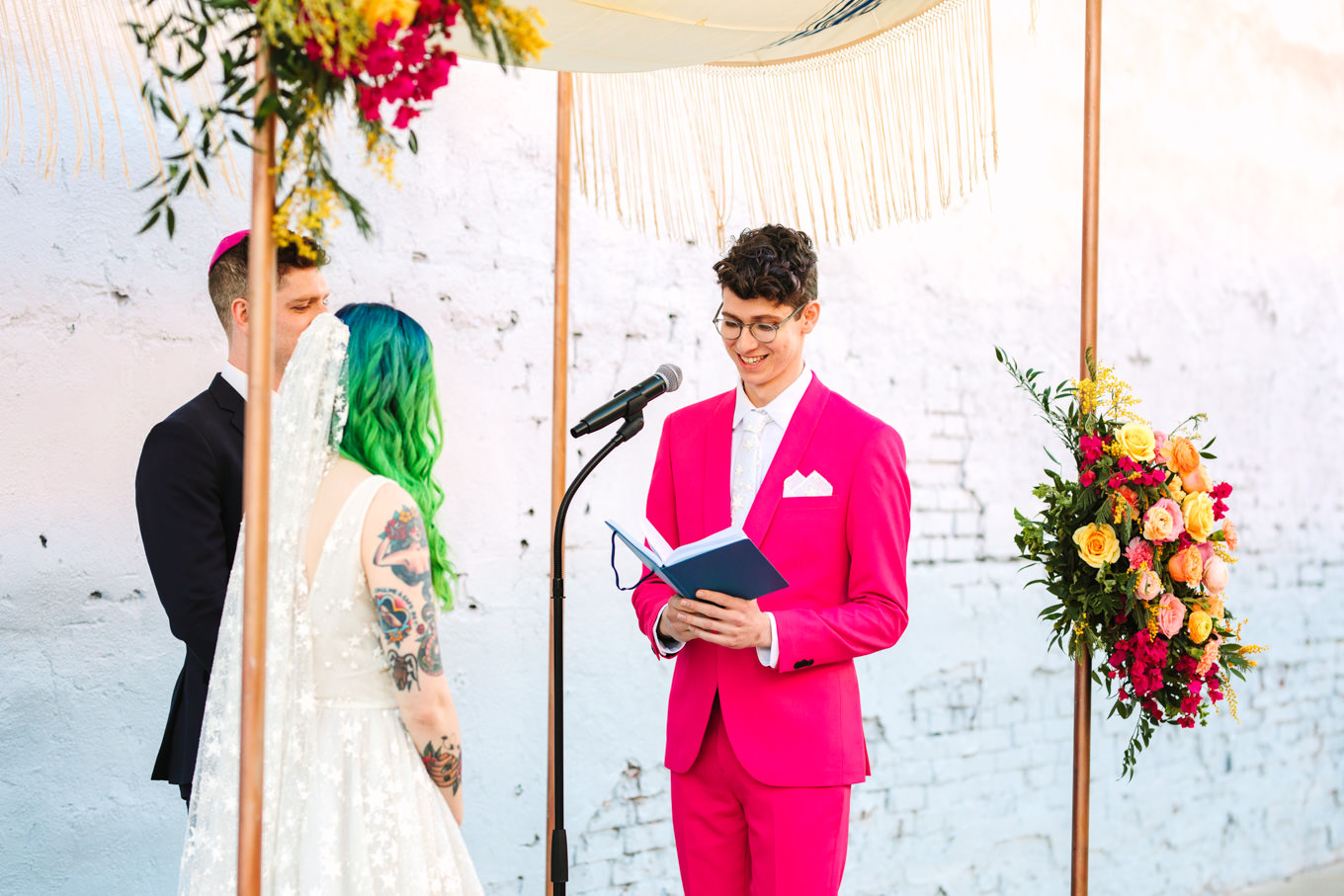 Groom in hot pink suit reading wedding vows | Colorful wedding at The Unique Space Los Angeles published in The Knot Magazine | Fresh and colorful photography for fun-loving couples in Southern California | #colorfulwedding #losangeleswedding #weddingphotography #uniquespace Source: Mary Costa Photography | Los Angeles