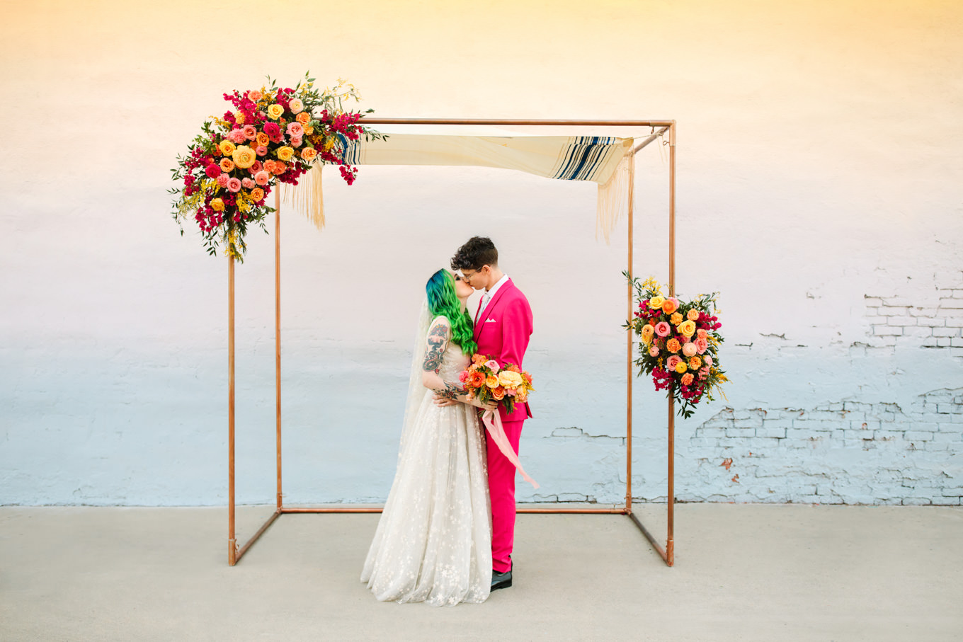 Bride and groom kissing under rectangle copper arch