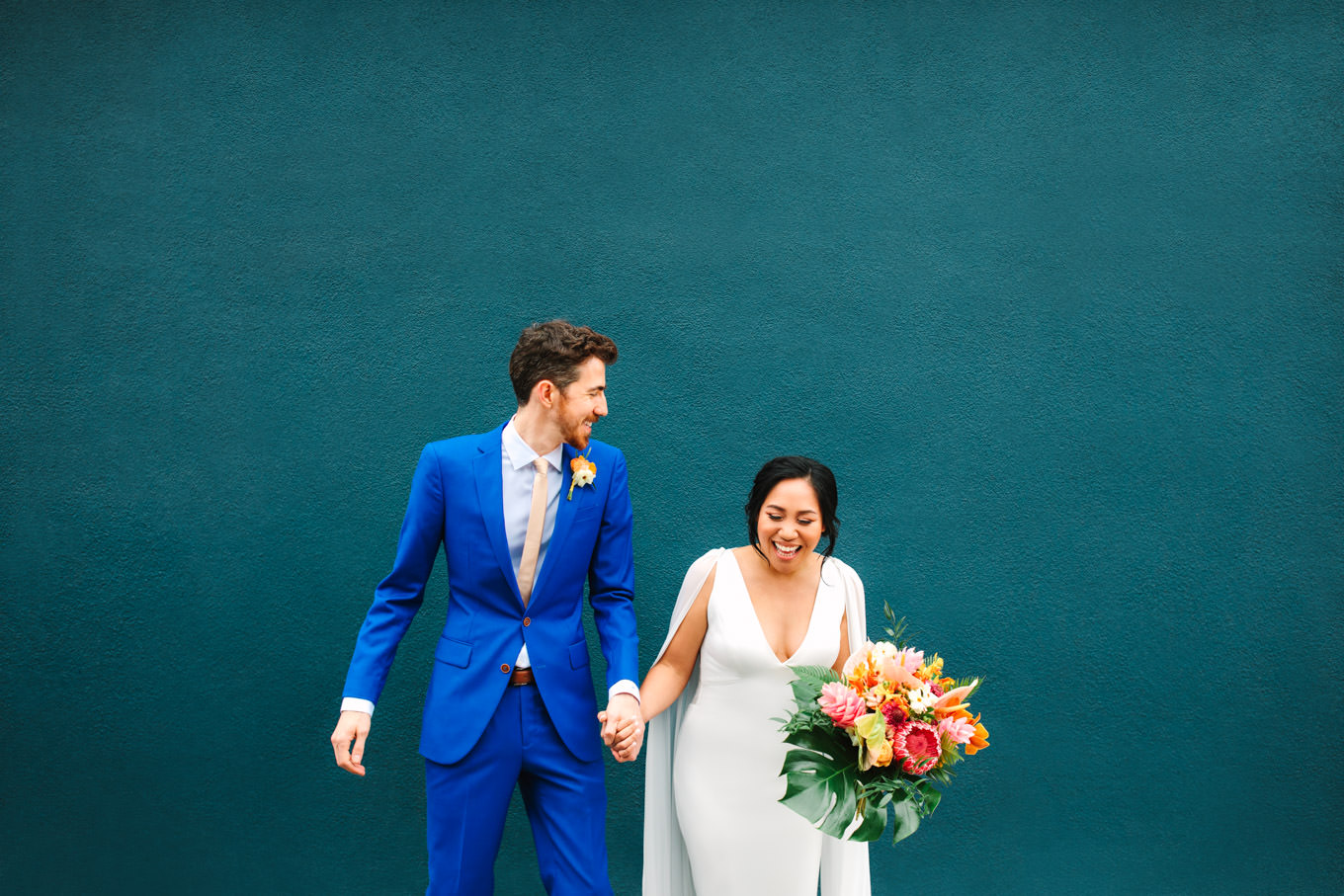 Bride and groom laughing in front of teal wall | TV inspired wedding at The Fig House Los Angeles | Published on The Knot | Fresh and colorful photography for fun-loving couples in Southern California | #losangeleswedding #TVwedding #colorfulwedding #theknot   Source: Mary Costa Photography | Los Angeles wedding photographer
