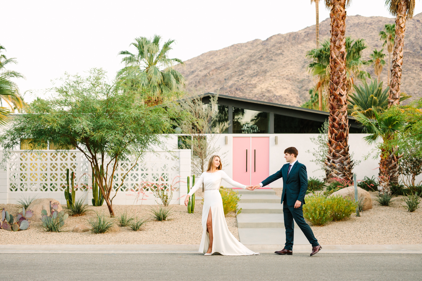 Bride and groom walking in front of pink door house | Colorful jewel tone Palm Springs elopement | Fresh and colorful photography for fun-loving couples in Southern California | #colorfulelopement #palmspringselopement #elopementphotography #palmspringswedding Source: Mary Costa Photography | Los Angeles
