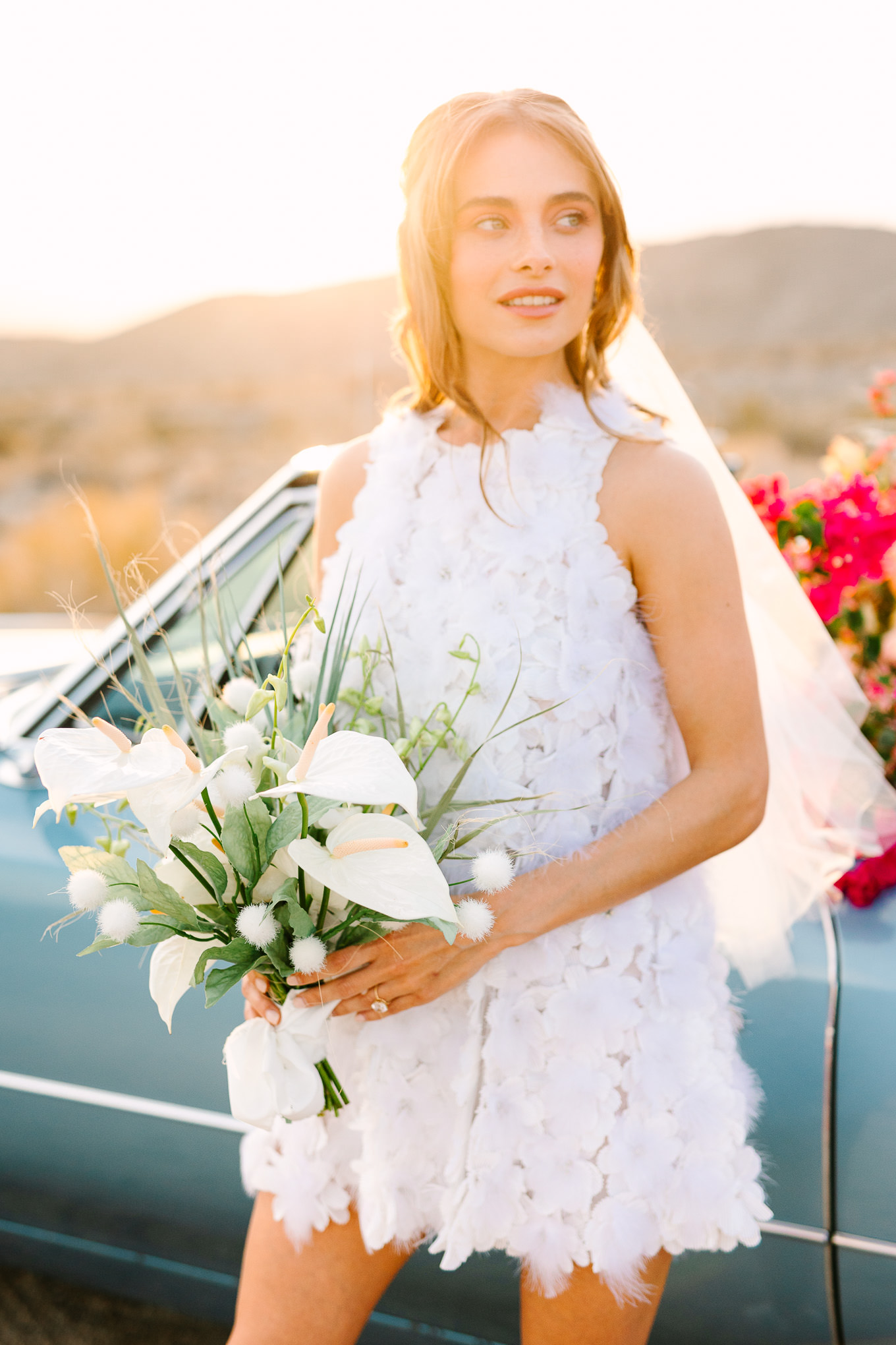 Colorful desert elopement bridal style with short Naeem Khan white dress and a blue classic car filled with flowers | Kindred Presets x Mary Costa Photography Palm Springs Ad Campaign | Colorful Palm Springs wedding photography | #palmspringsphotographer #lightroompresets #sandshotel #pinkhotel   Source: Mary Costa Photography | Los Angeles