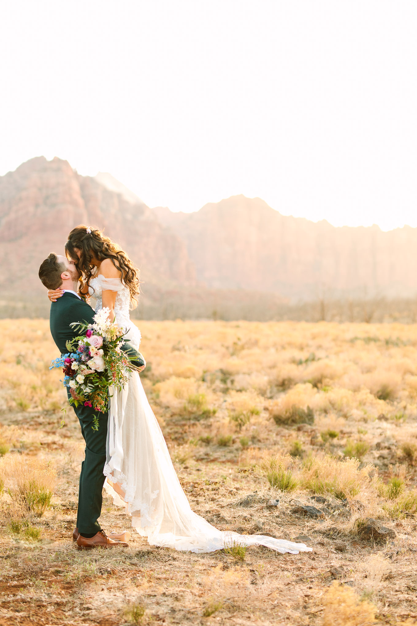 Bride with groom in green suit portraits | Zion Under Canvas camping elopement at sunrise | Colorful elopement photography | #utahelopement #zionelopement #zionwedding #undercanvaszion #sunriseelopement #adventureelopement  Source: Mary Costa Photography | Los Angeles