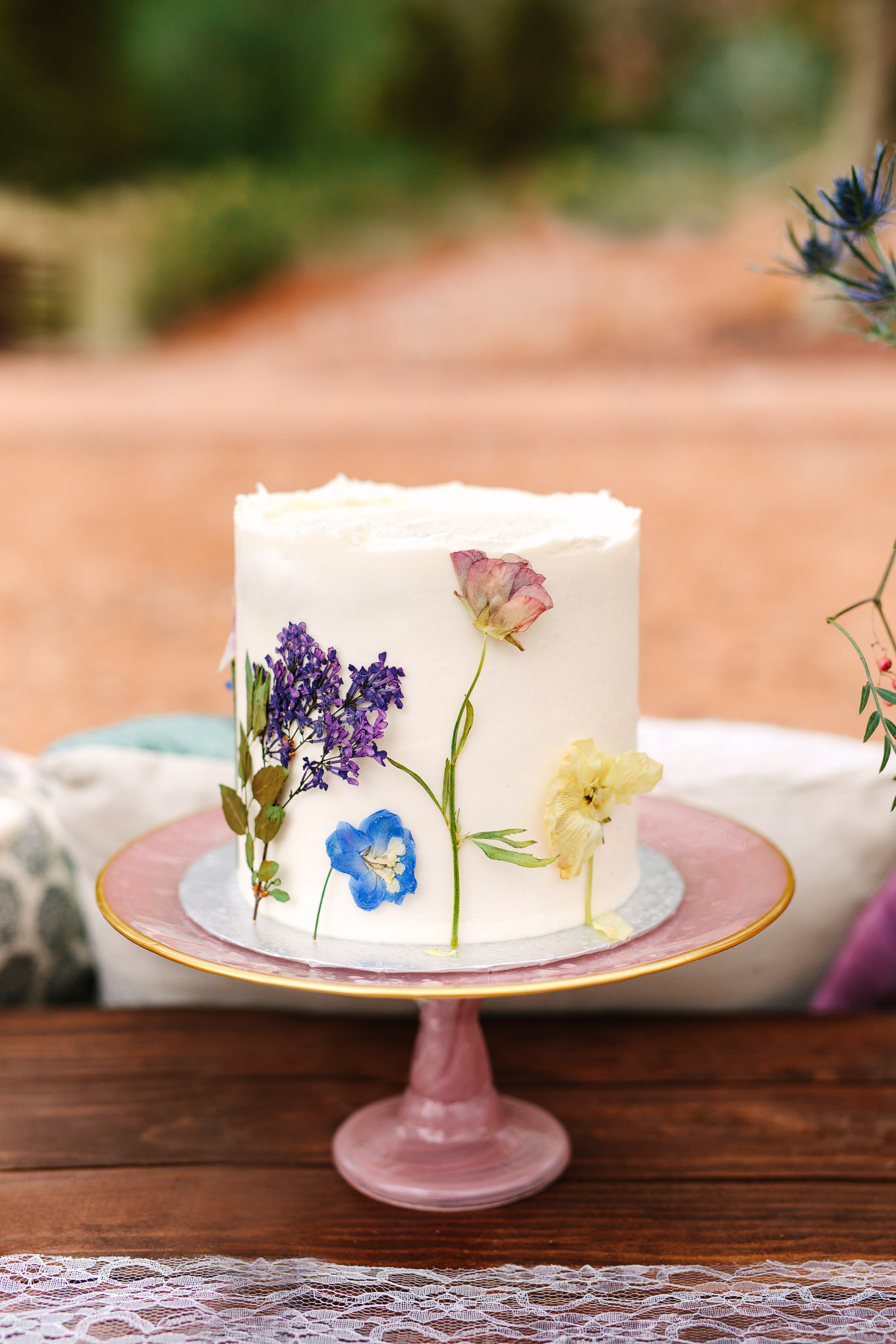 Pressed flower cake for purple and jewel tone picnic setup | Zion National Park elopement | Colorful adventure elopement photography | #utahelopement #zionelopement #zionwedding #undercanvaszion #picnicwedding  Source: Mary Costa Photography | Los Angeles