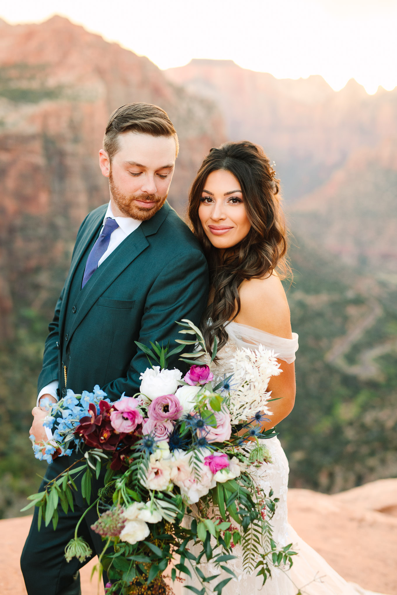 Groom in green suit with colorful bouquet bride | Zion National Park sunset elopement scenic overlook | Colorful adventure elopement photography | #utahelopement #zionelopement #zionwedding #undercanvaszion   Source: Mary Costa Photography | Los Angeles