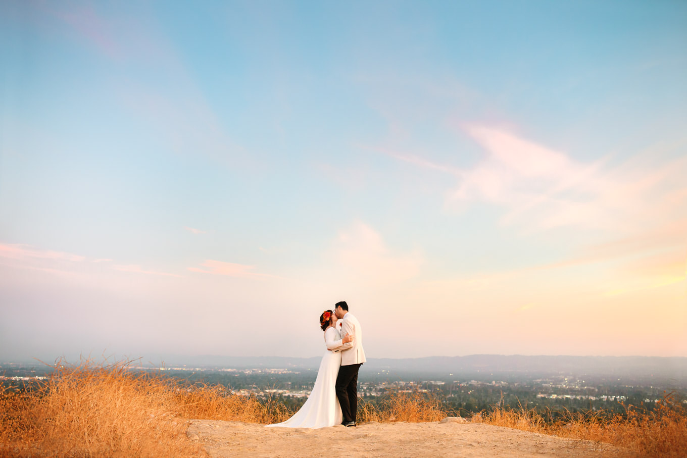 Bride and groom share a kiss with cityscape as backdrop | Vibrant backyard micro wedding featured on Green Wedding Shoes | Colorful LA wedding photography | #losangeleswedding #backyardwedding #microwedding #laweddingphotographer Source: Mary Costa Photography | Los Angeles