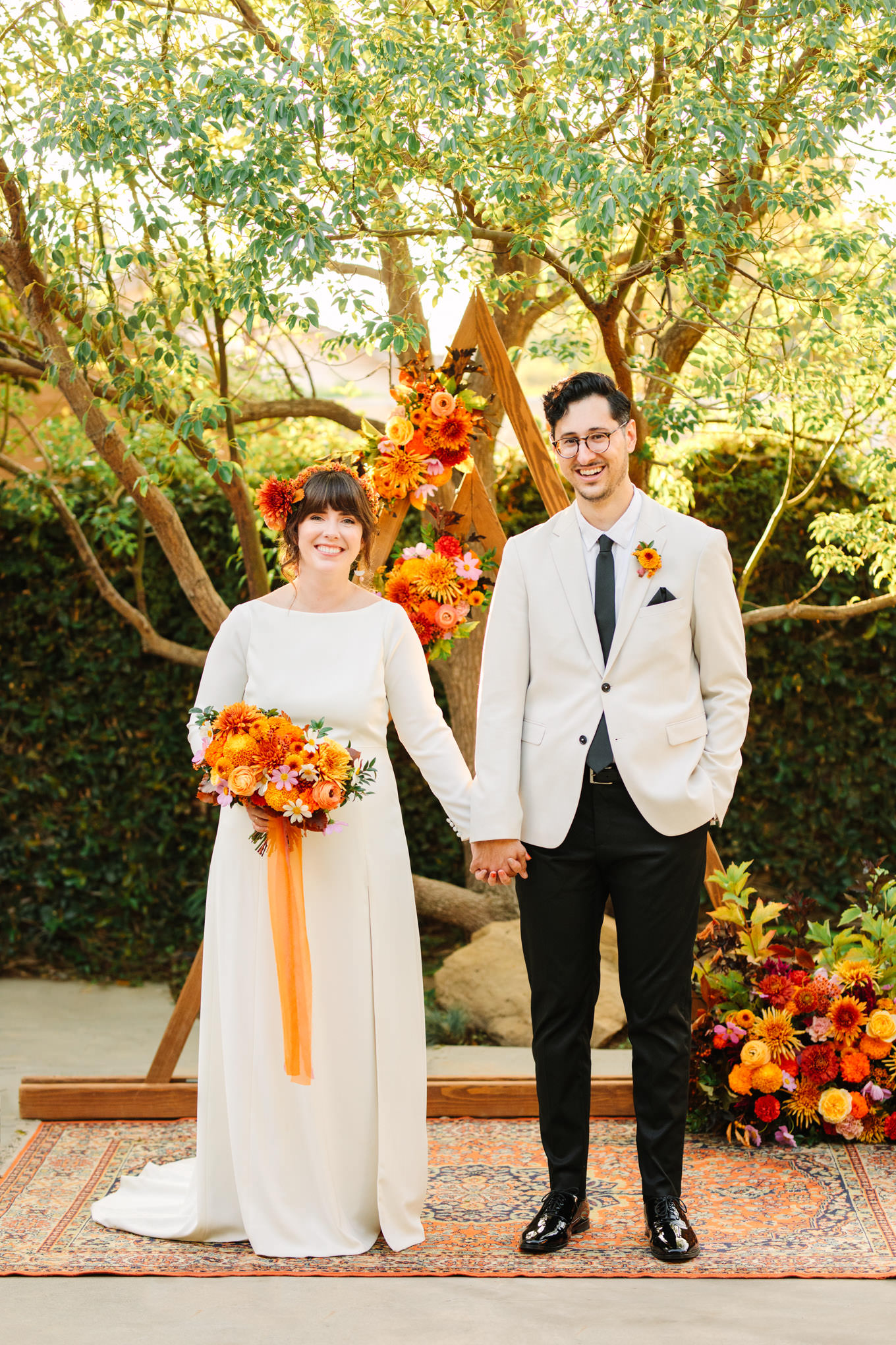 Bride and groom holding hands with unique backdrop | Vibrant backyard micro wedding featured on Green Wedding Shoes | Colorful LA wedding photography | #losangeleswedding #backyardwedding #microwedding #laweddingphotographer Source: Mary Costa Photography | Los Angeles
