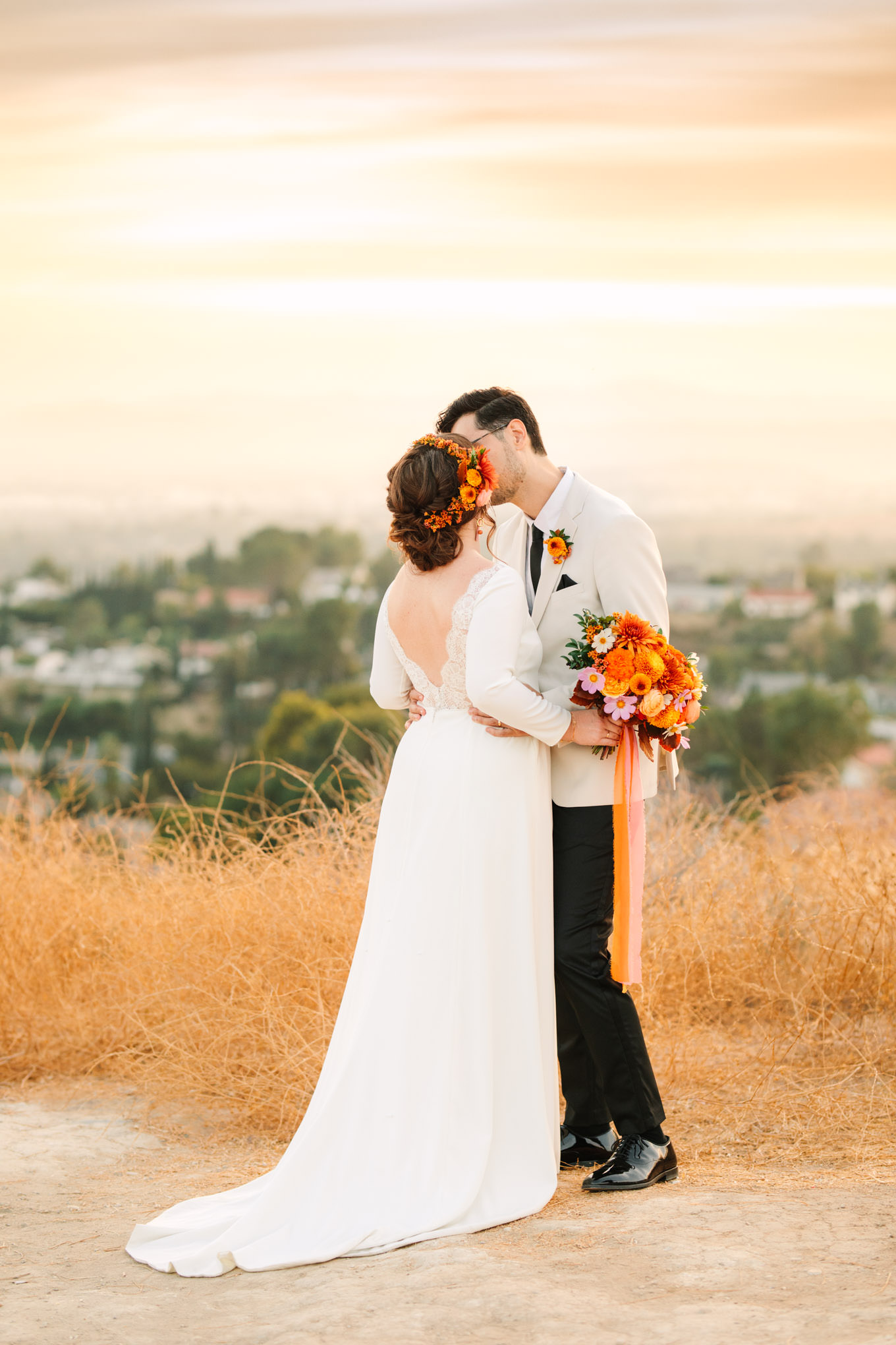 Bride and groom with cityscape backdrop share a kiss | Vibrant backyard micro wedding featured on Green Wedding Shoes | Colorful LA wedding photography | #losangeleswedding #backyardwedding #microwedding #laweddingphotographer Source: Mary Costa Photography | Los Angeles